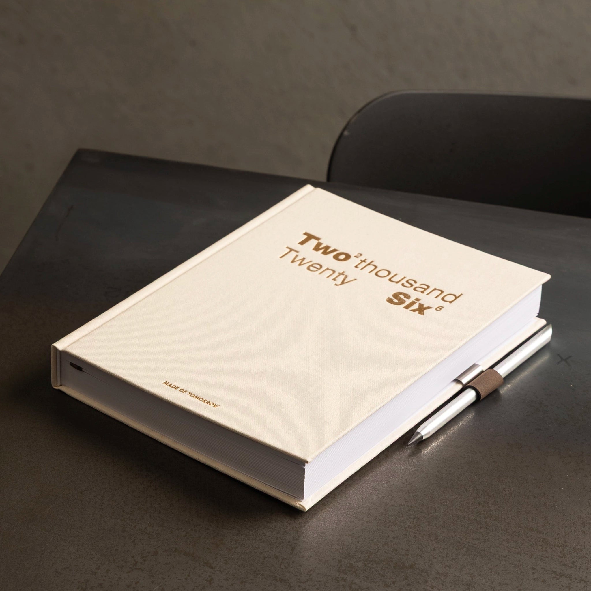 Beige notebook with 'Two Thousand Six' on a dark surface