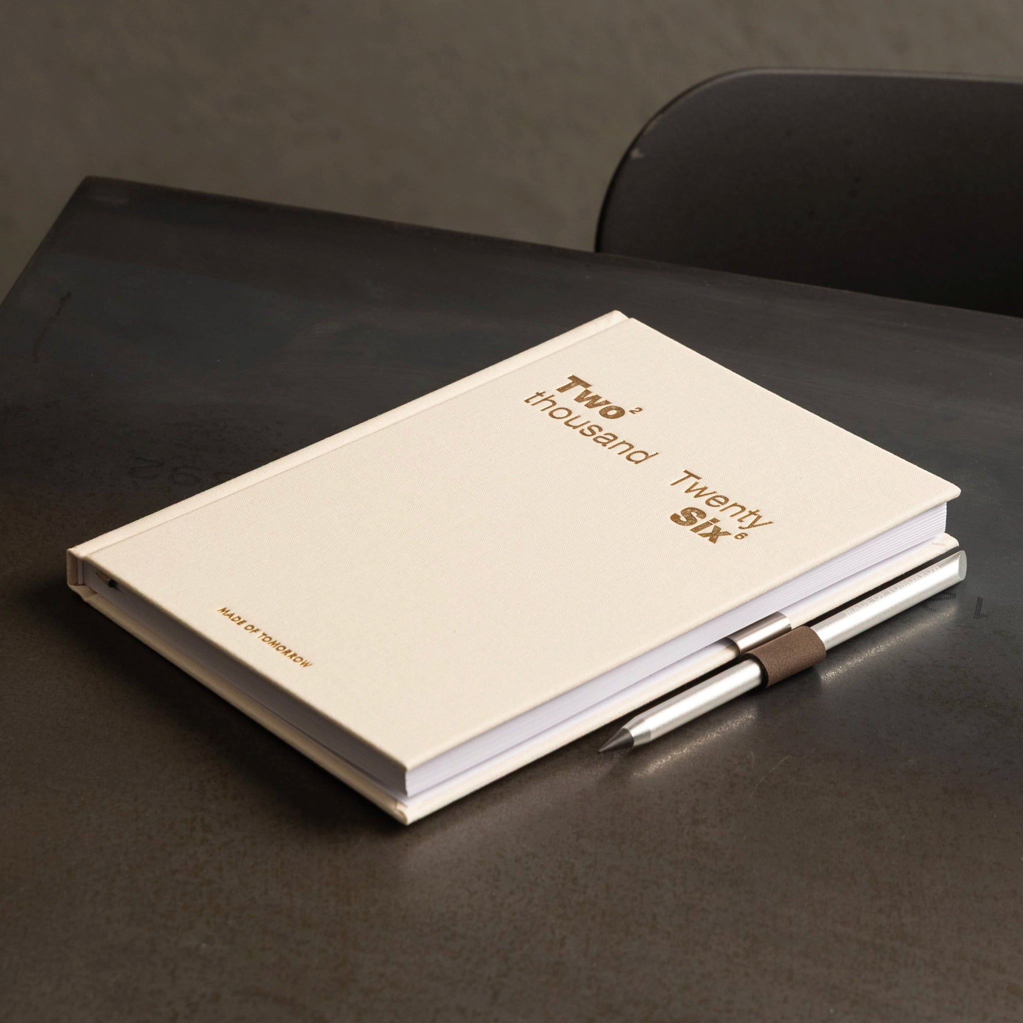 Beige notebook with 'Two thousand Twenty six' text on a dark surface