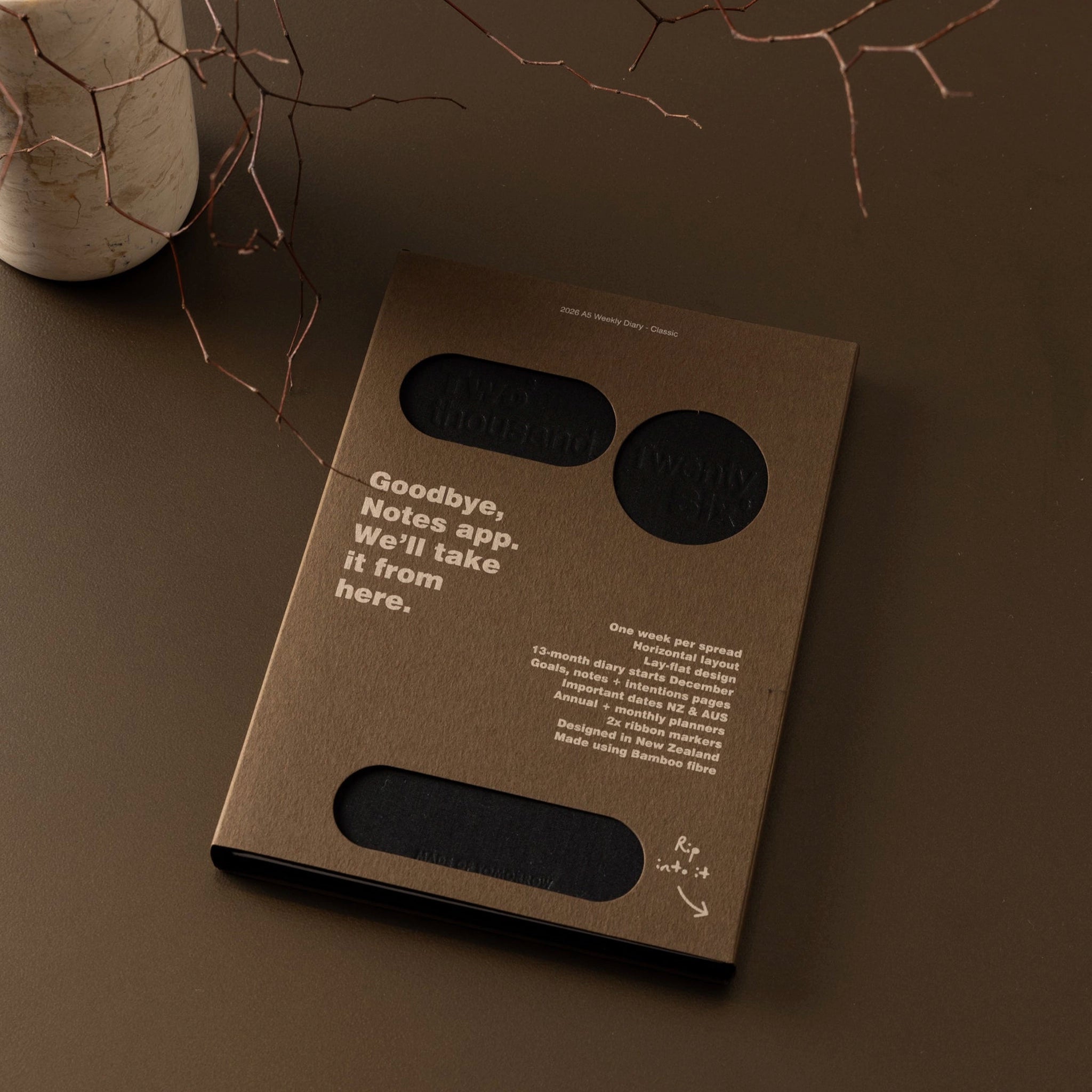Black notebook with 'Two thousand Twenty Six' text on a brown background