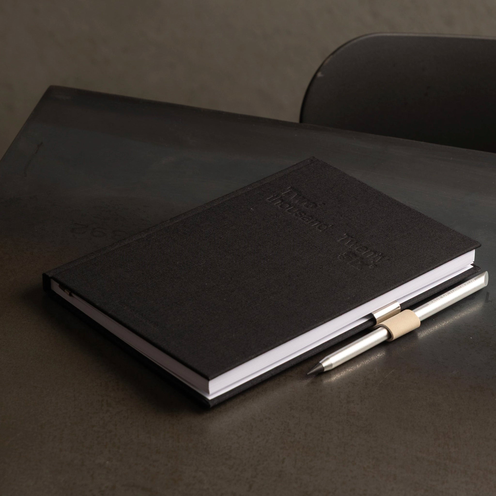 Black leather notebook with a pen on a dark surface