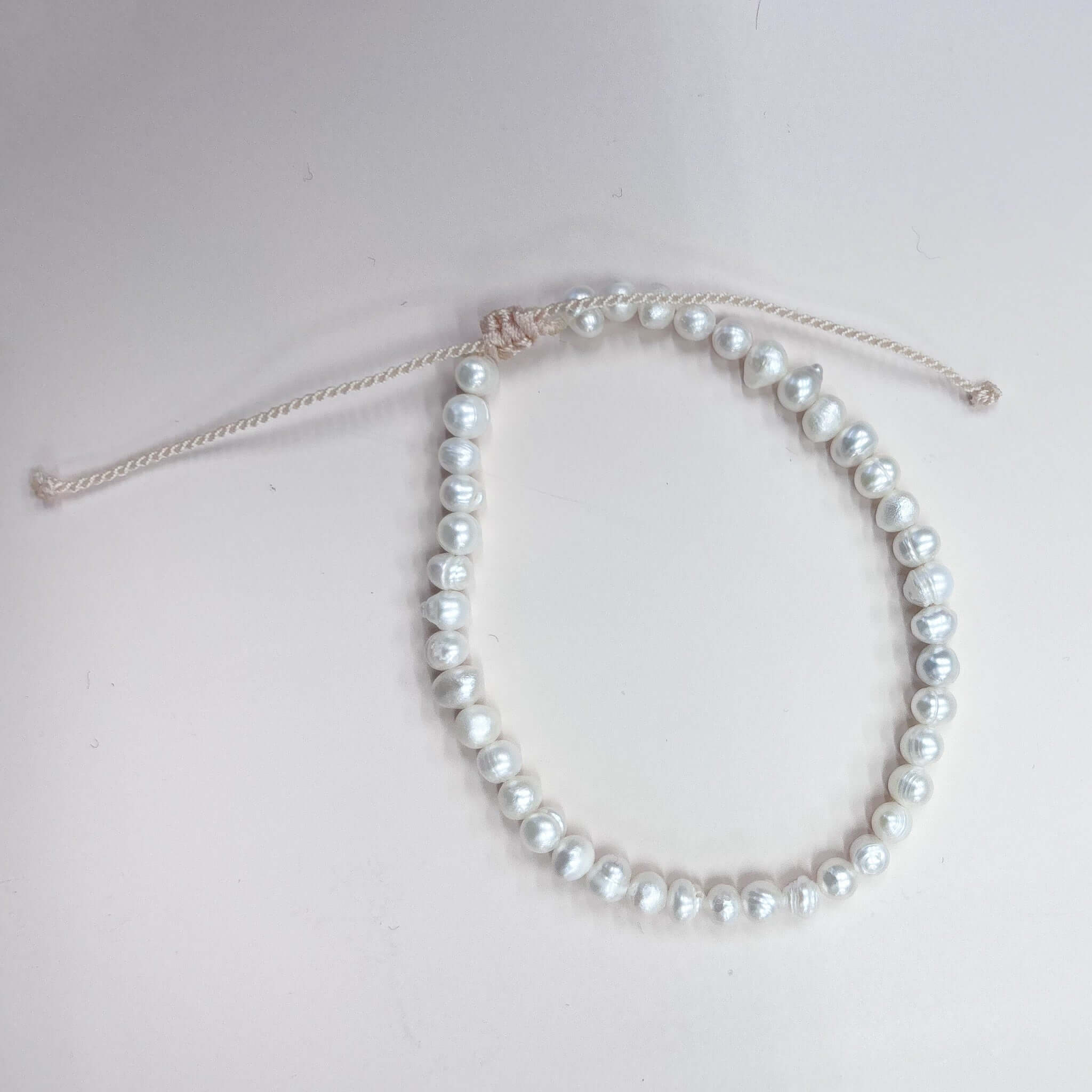 Margaret Pearl Bracelet featuring freshwater pearls on an adjustable white cord closure.
