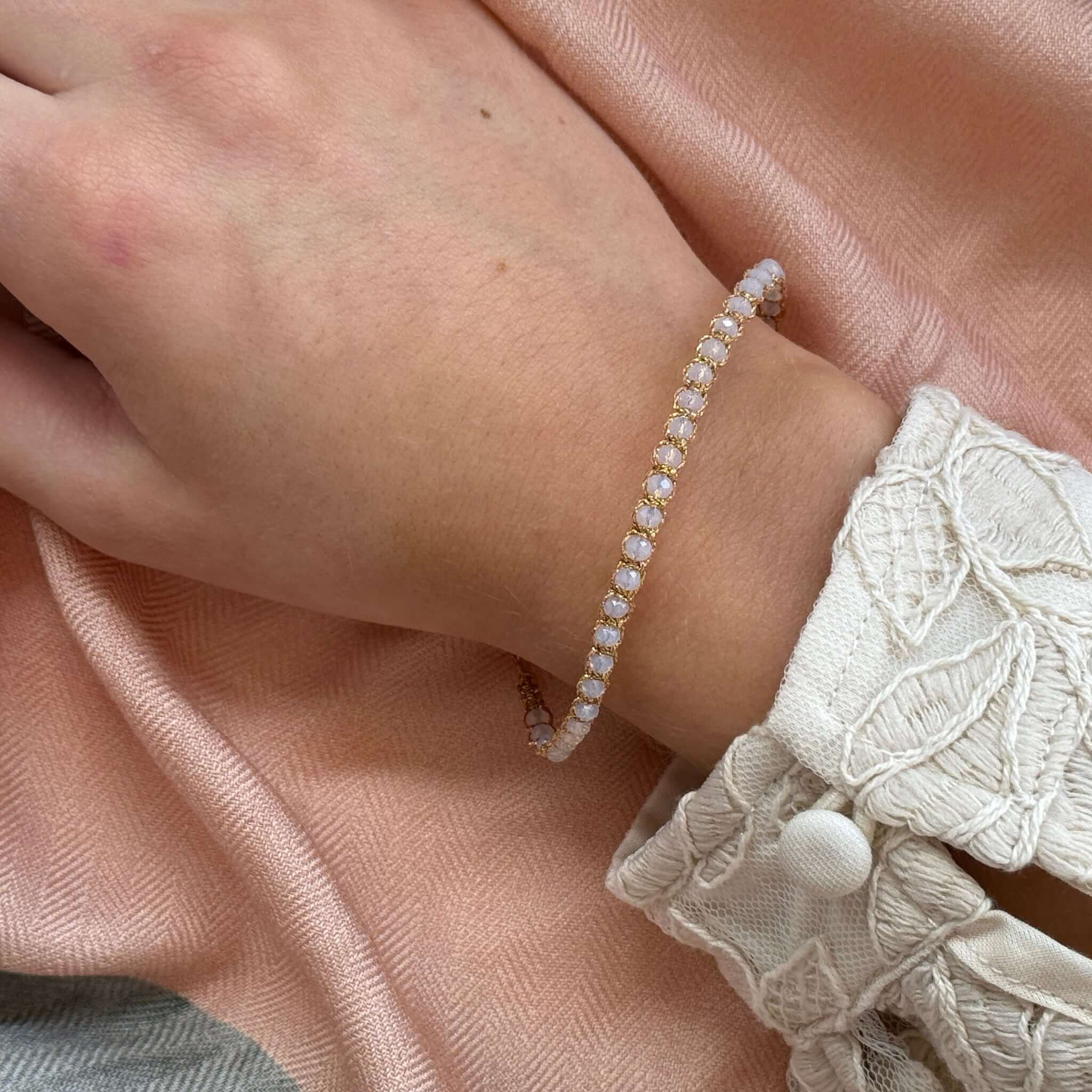 Margaret Adeline Bracelet featuring delicate faceted crystals on a wrist with a pink fabric background.