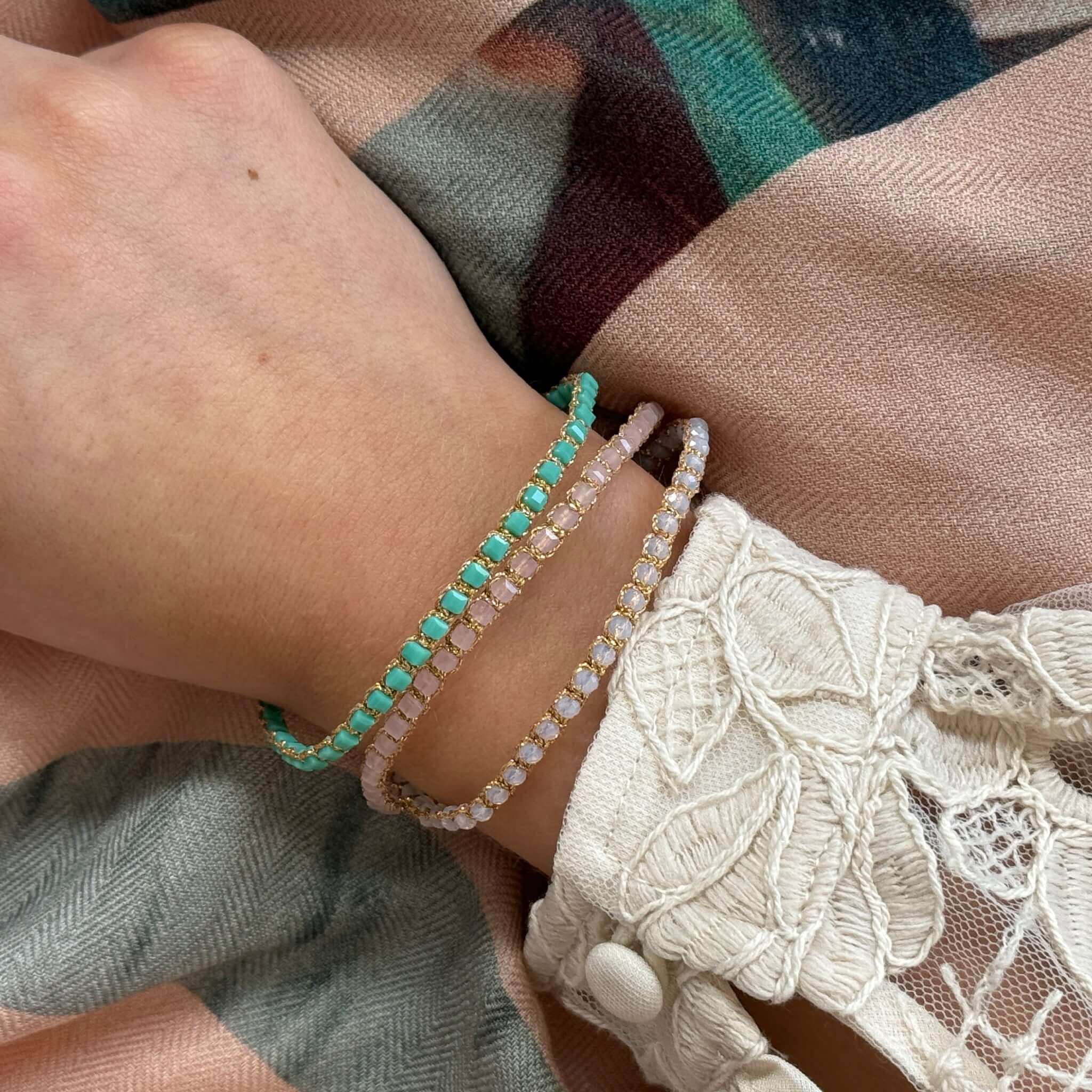 Hand wearing Margaret Adeline Bracelet in various colors, showcasing delicate crystals and fine gold thread.