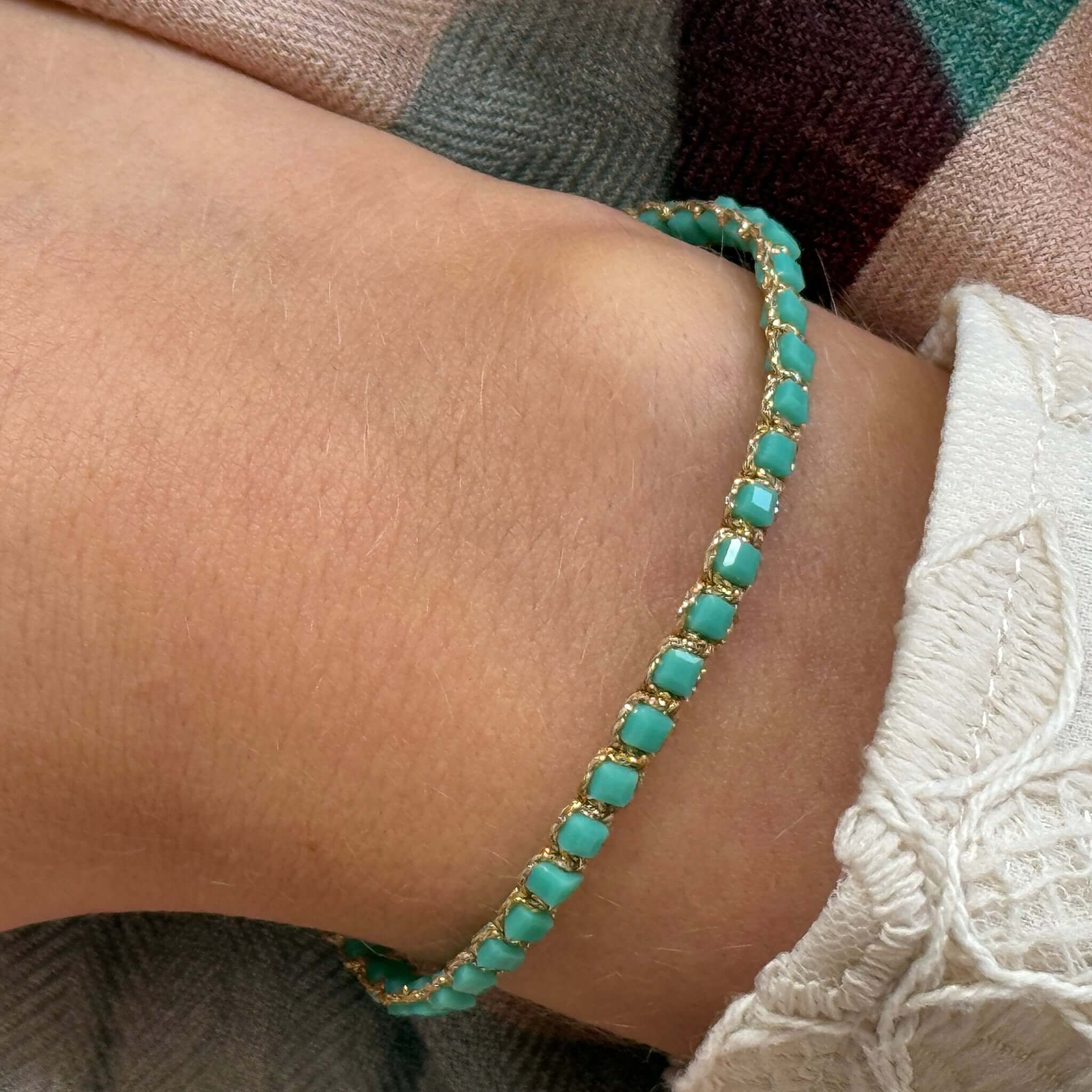 Margaret Adeline Bracelet showcasing turquoise crystals on a fine gold thread cord worn on a wrist.