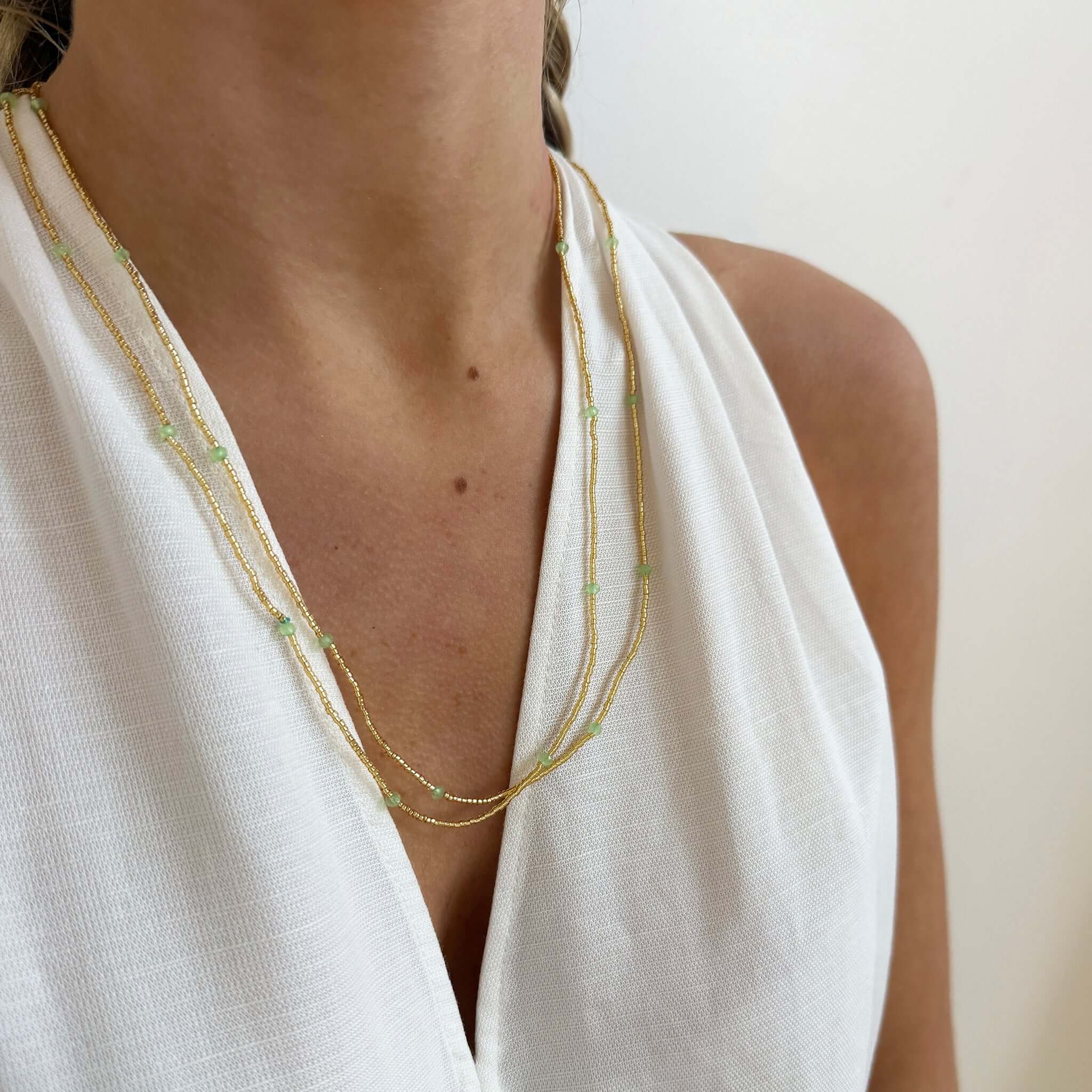 Margaret Dorothy Necklace worn layered with green accent beads against a white top.