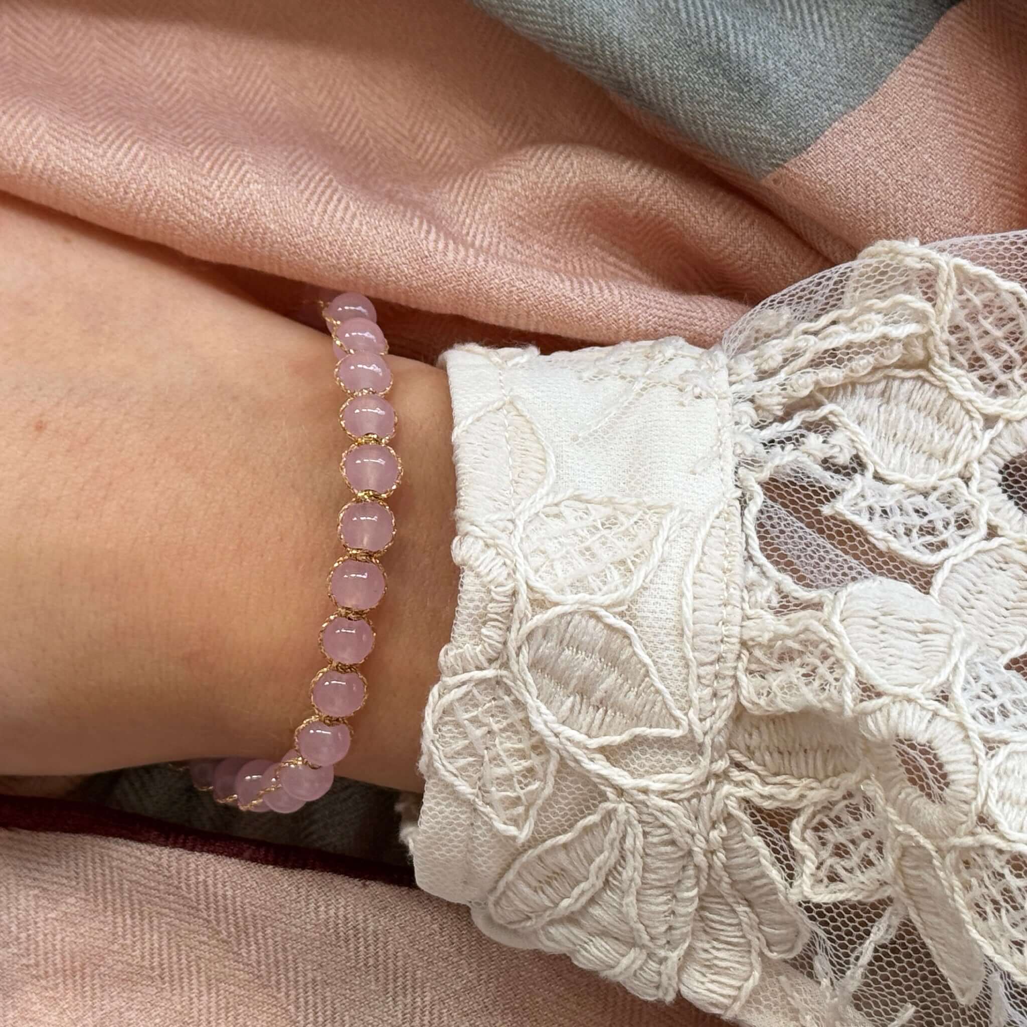 Close-up of the Margaret Edna Bracelet featuring chunky beads and fine gold cord on a wrist adorned with lace.