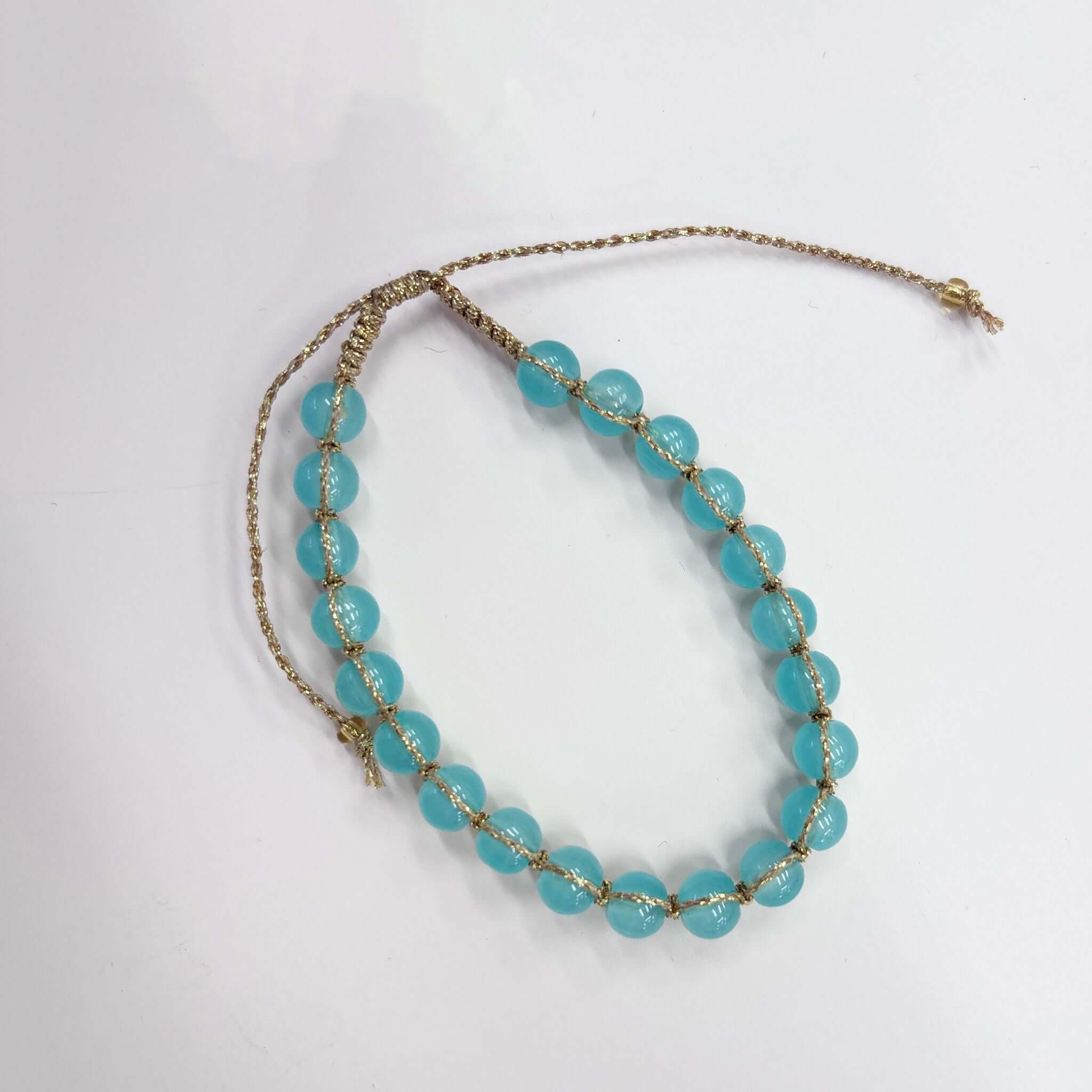 Margaret Edna Bracelet featuring chunky turquoise beads on gold cord with adjustable closure.