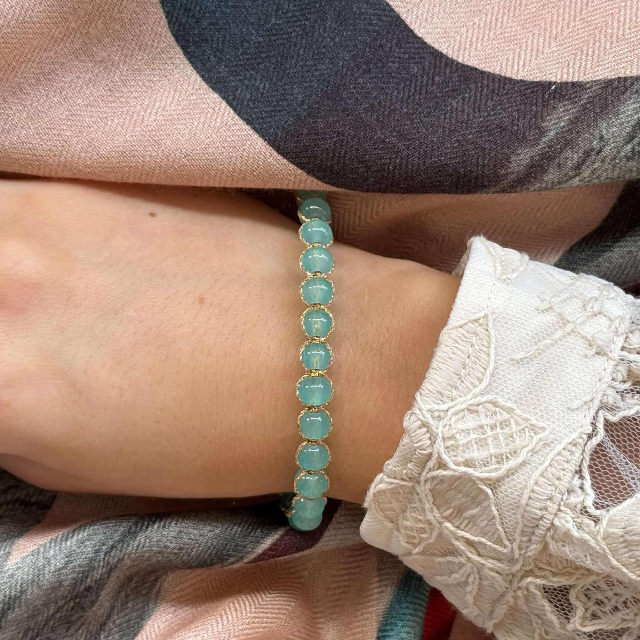 Margaret Edna Bracelet worn on a hand, featuring chunky beads in soft muted tones and a fine gold cord.