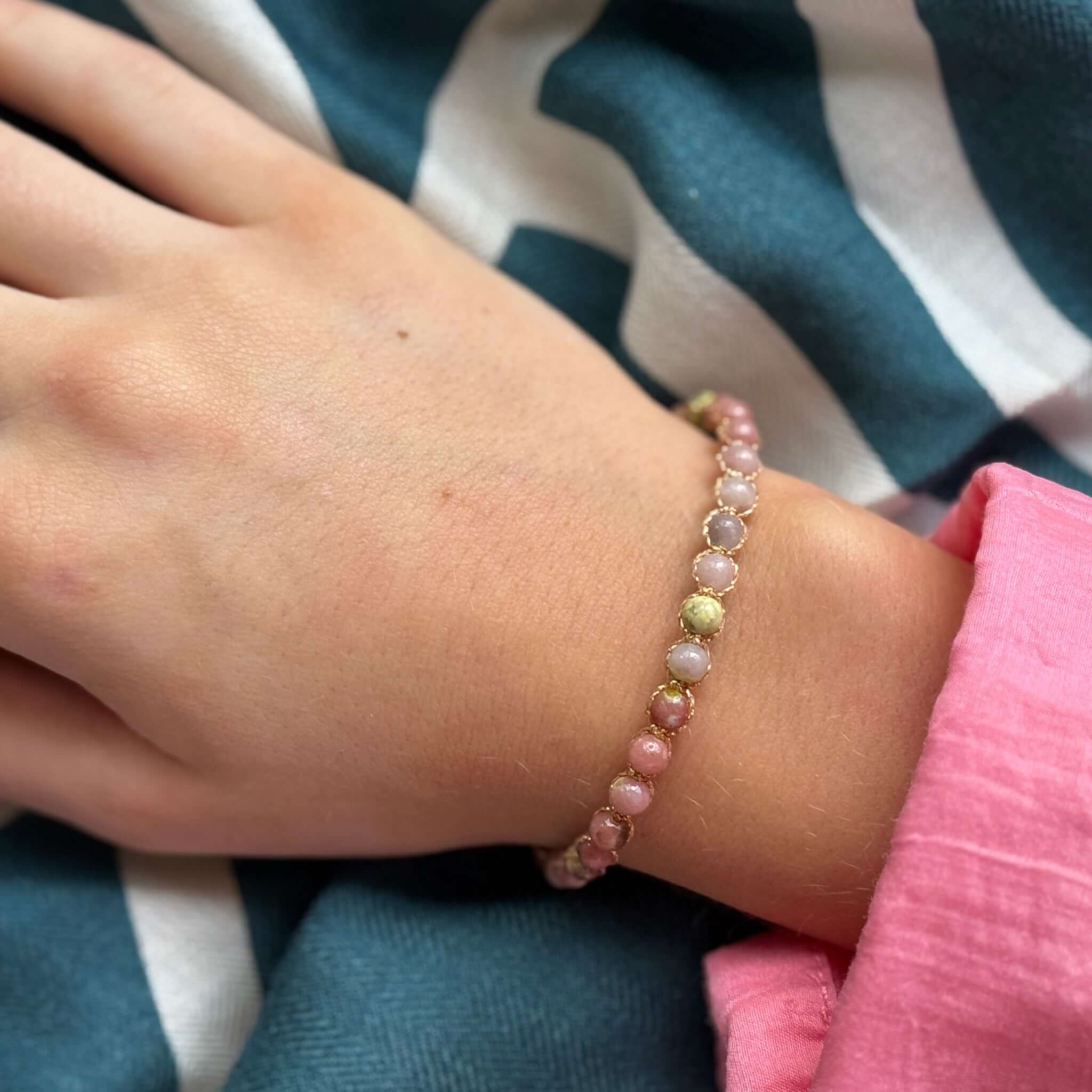 Margaret Ellen Bracelet featuring smooth round stone beads on a wrist with soft colors and delicate gold thread setting.