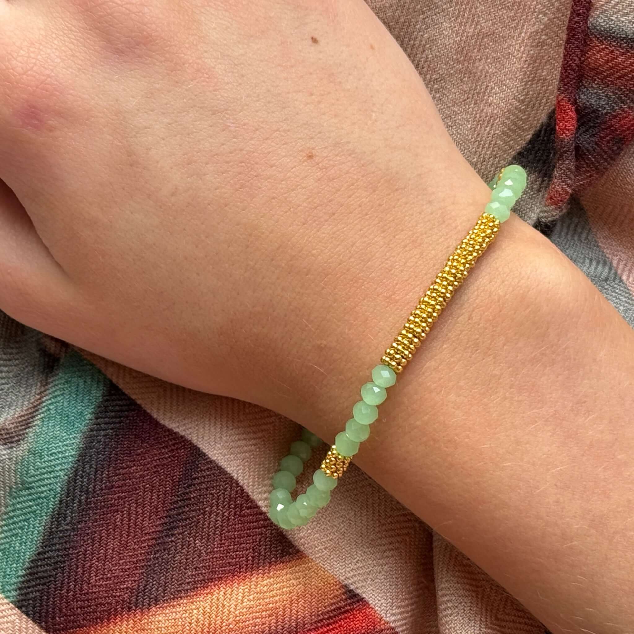 Margaret Lola Bracelet showcased on a hand with a woven gold bead bar and mint crystal beads.
