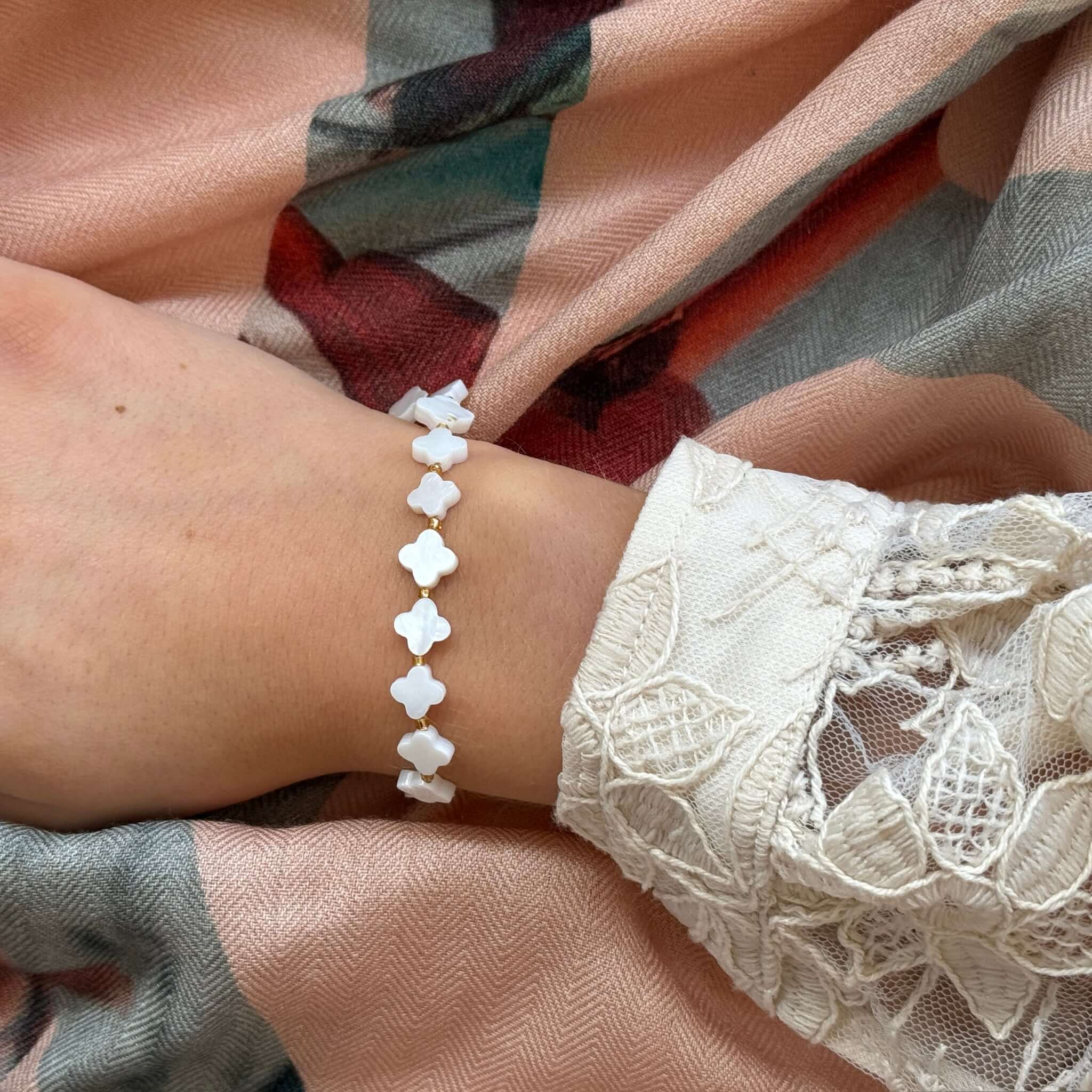 Margaret Shell Bracelet featuring mother-of-pearl clover-shaped beads on a wrist with lace detail.