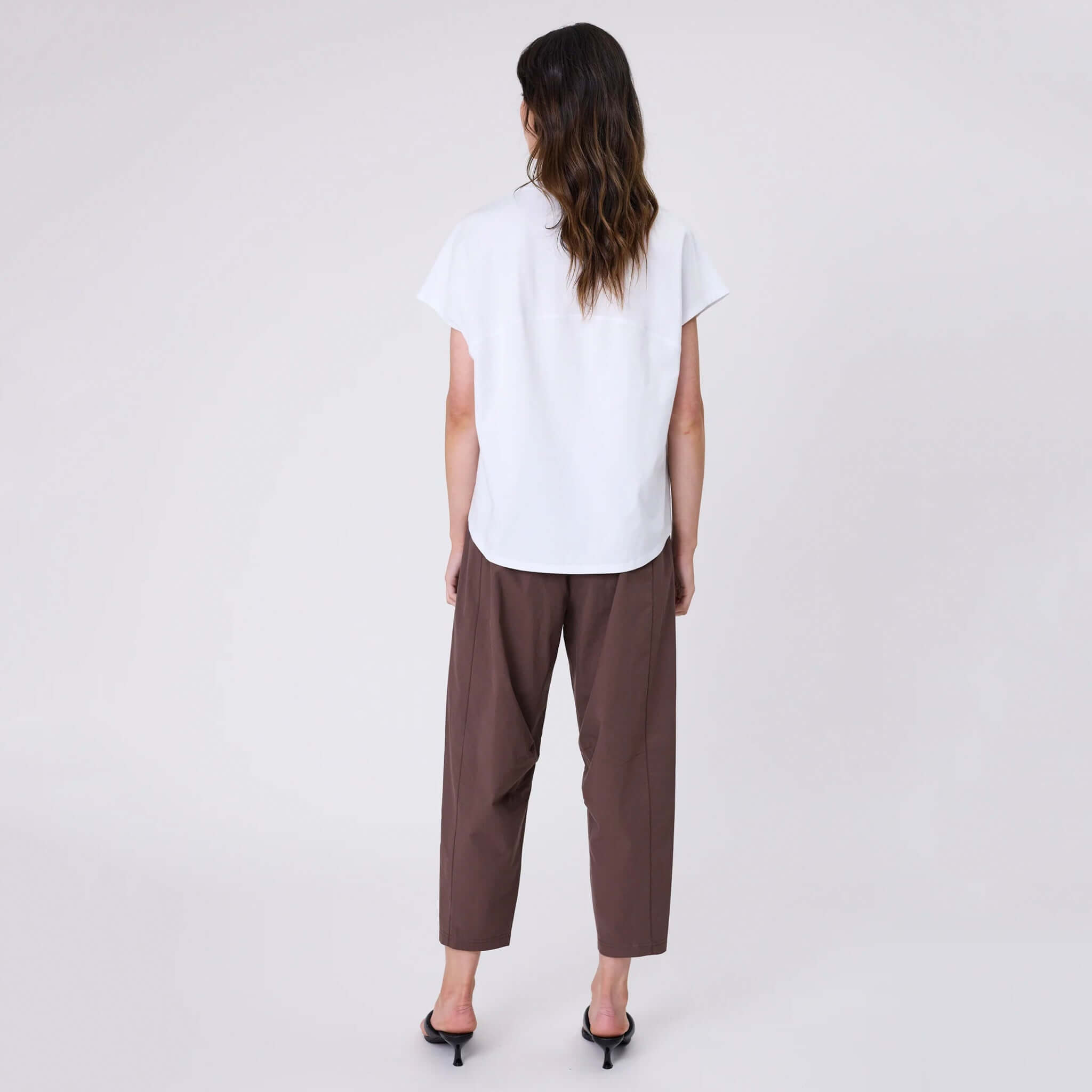 Marlow Barrel Tee - White showcased with brown trousers from the back, featuring a relaxed fit and soft cotton material.