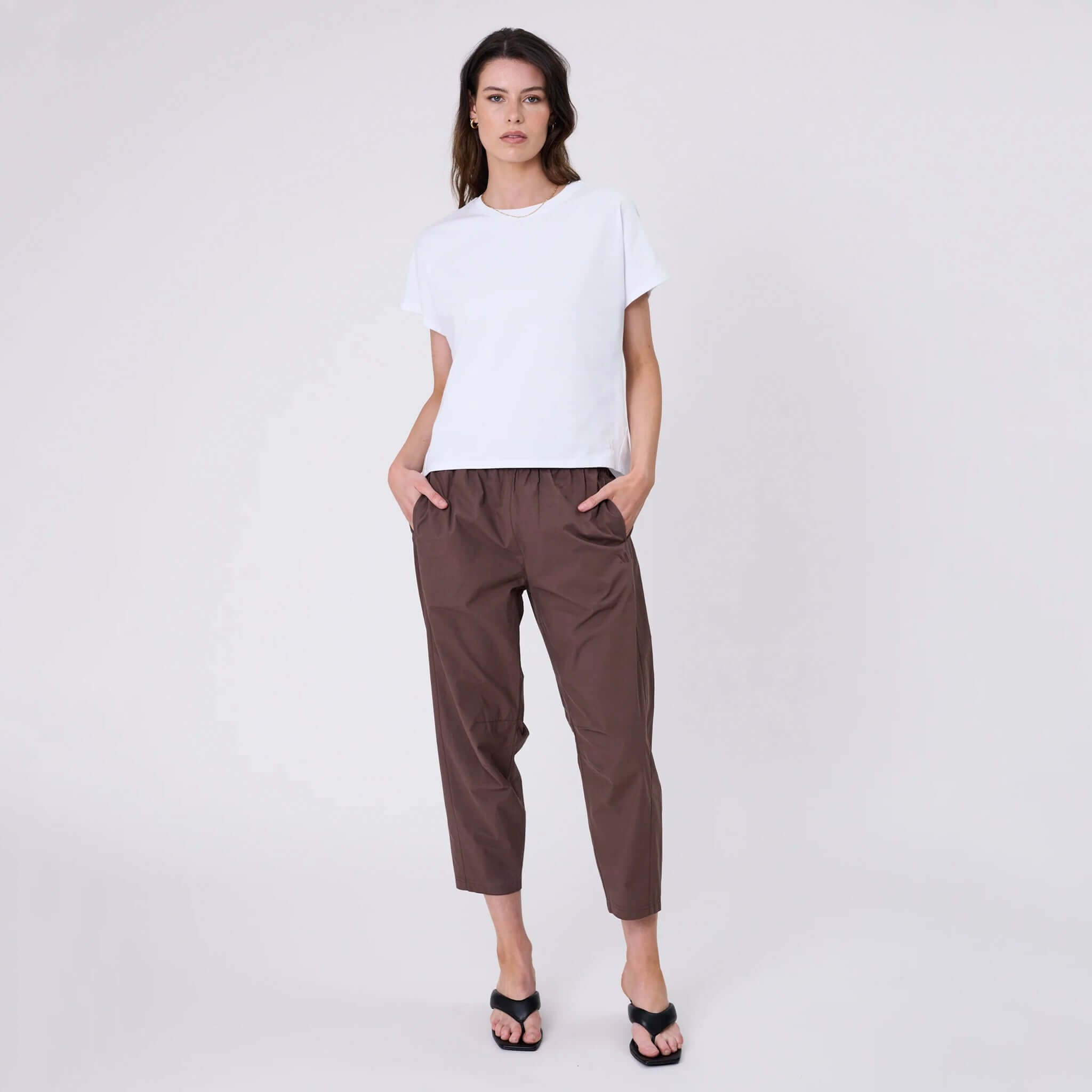 Model wearing a relaxed fit Marlow Barrel Tee - White paired with brown trousers.