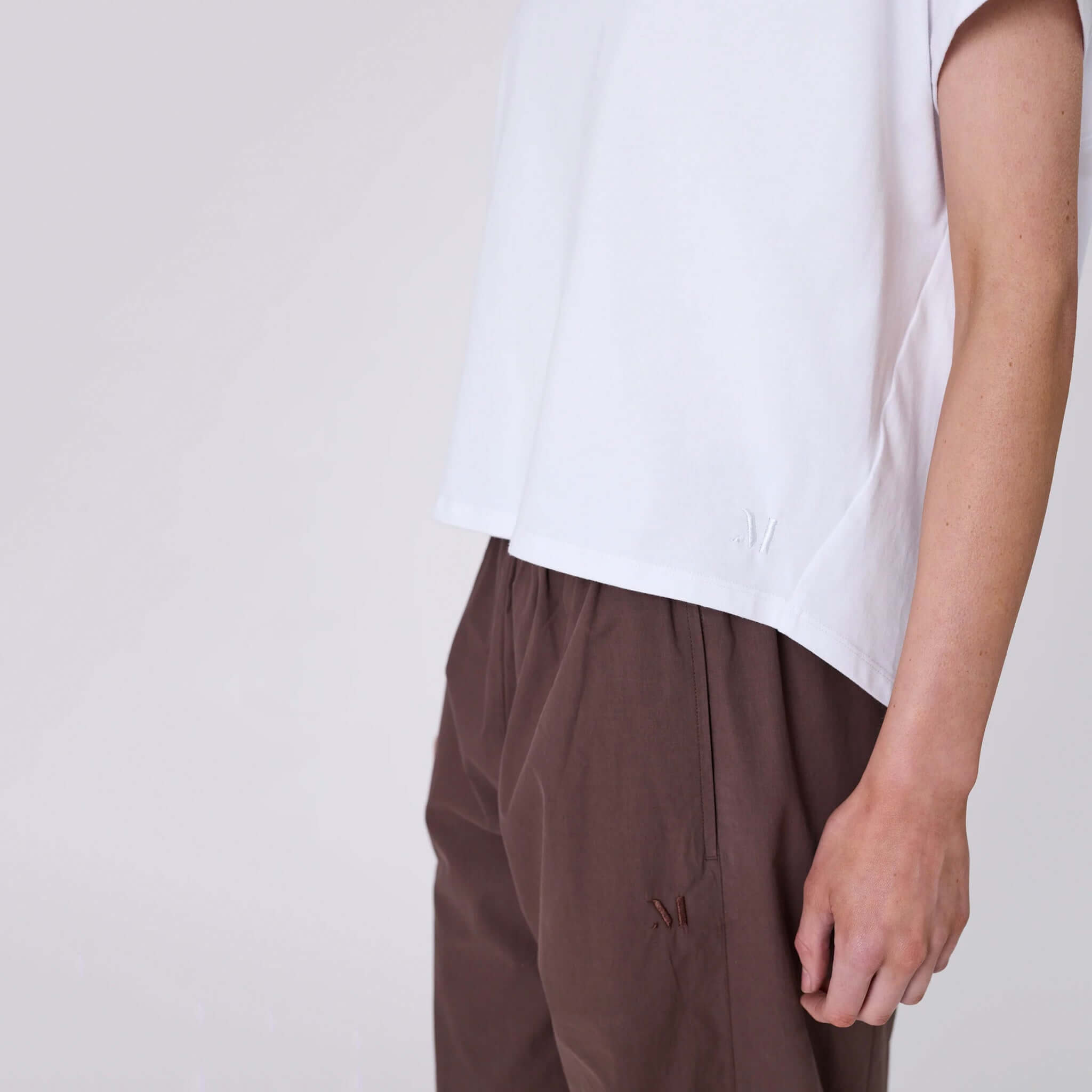 Marlow Barrel Tee - White, showing a relaxed fit and curved hem, paired with brown trousers.