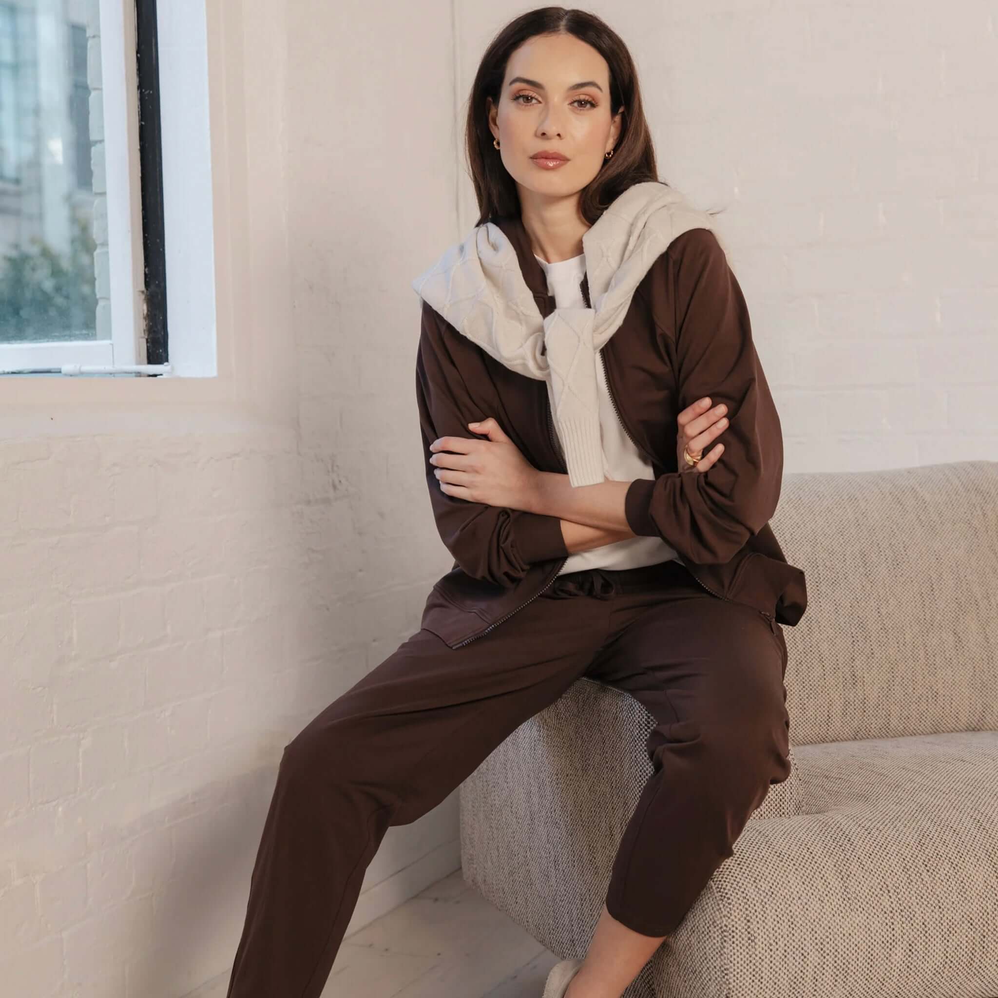 Woman wearing Marlow Barrel Trackie - Java, featuring a relaxed fit and stylish detailing in a cozy setting.