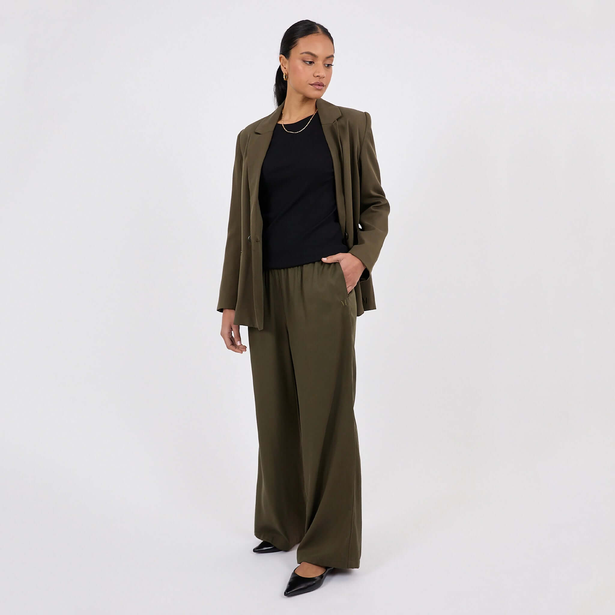 Model wearing Marlow Eclipse Wide Leg Pants - Spruce with black top and blazer, showcasing a polished, comfortable style.