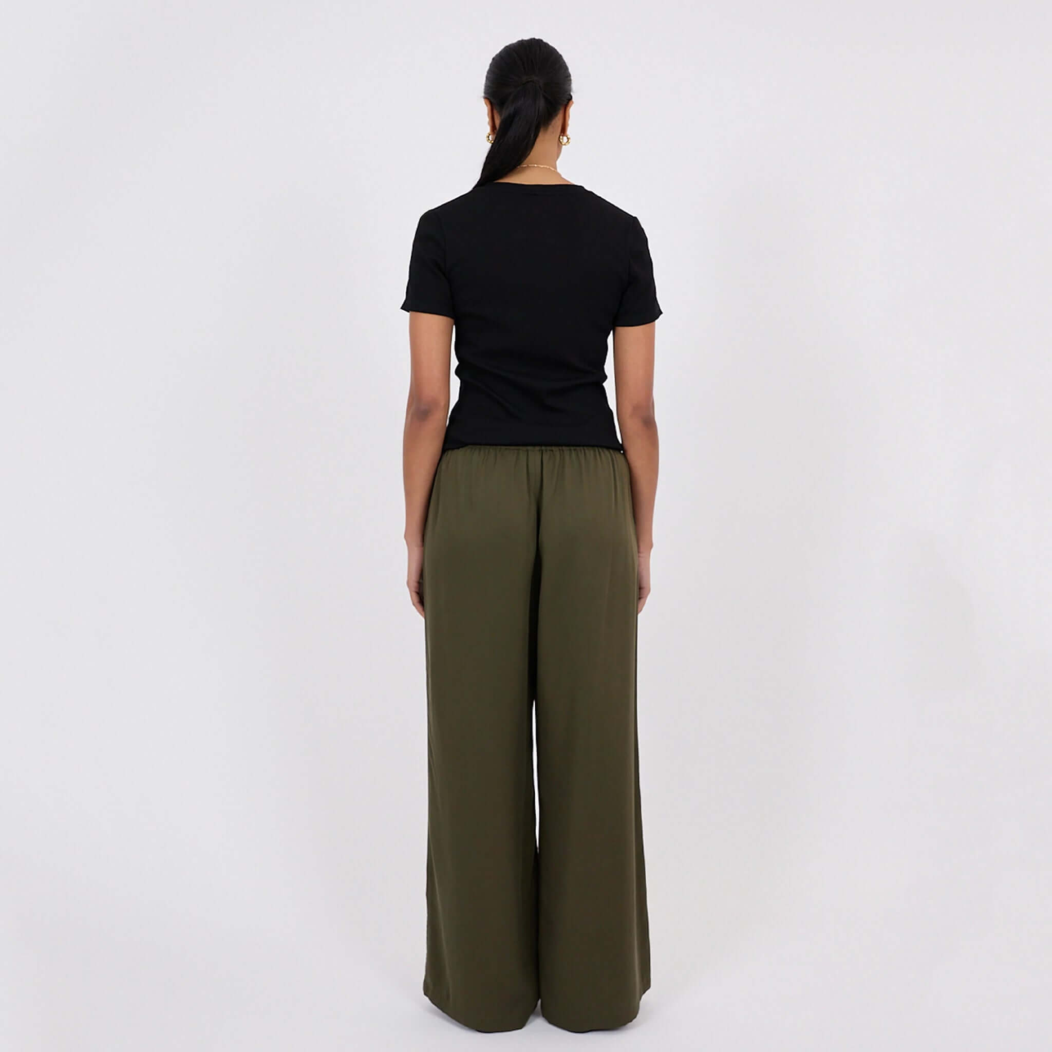 Woman wearing Marlow Eclipse Wide Leg Pants - Spruce, viewed from the back, showcasing the fluid drape and wide-leg design.
