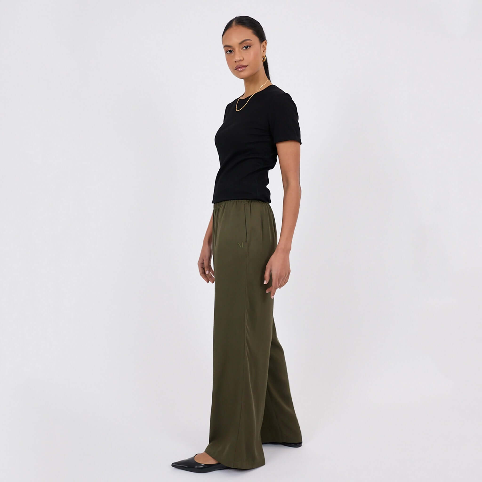 Marlow Eclipse Wide Leg Pants - Spruce worn by model with black t-shirt and flats, showcasing effortless style.