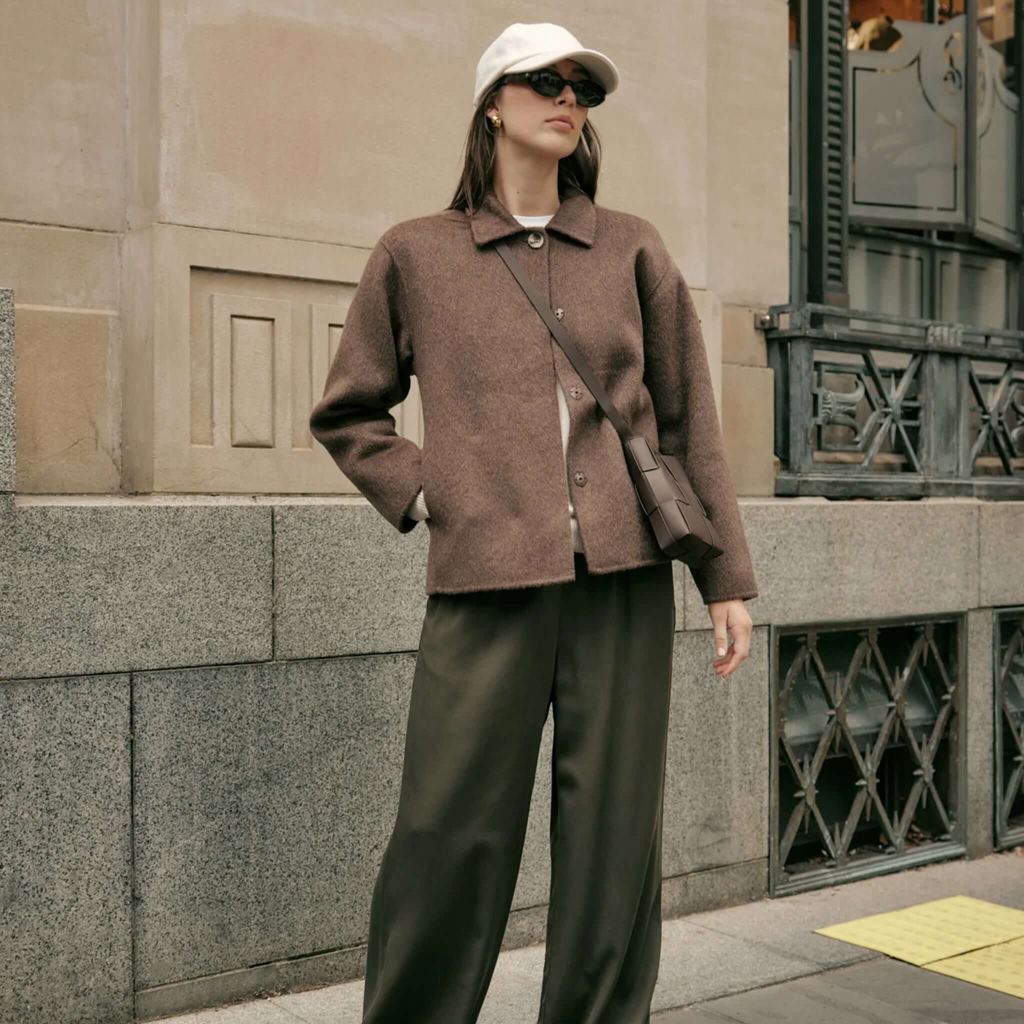 Model wearing Marlow Loft Wool Coat - Mushroom with trendy sunglasses and a cap on a city street.