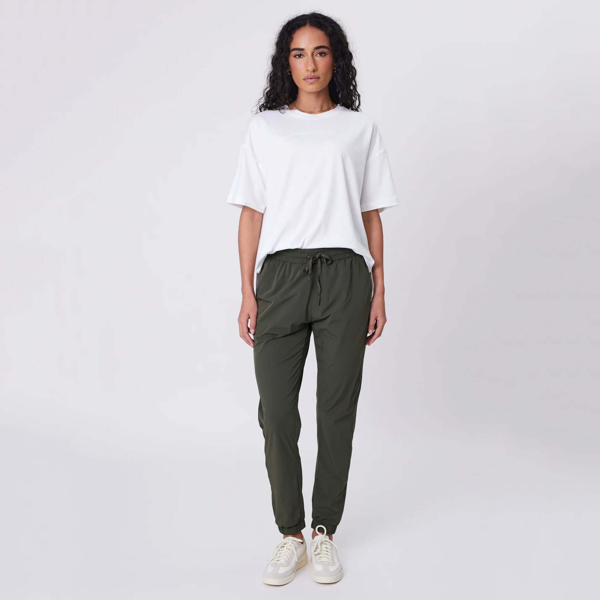 Alt Tag: Marlow Travel Pants - Olive on model, featherlight stretch tapered travel pants with drawstring waist and zip pockets