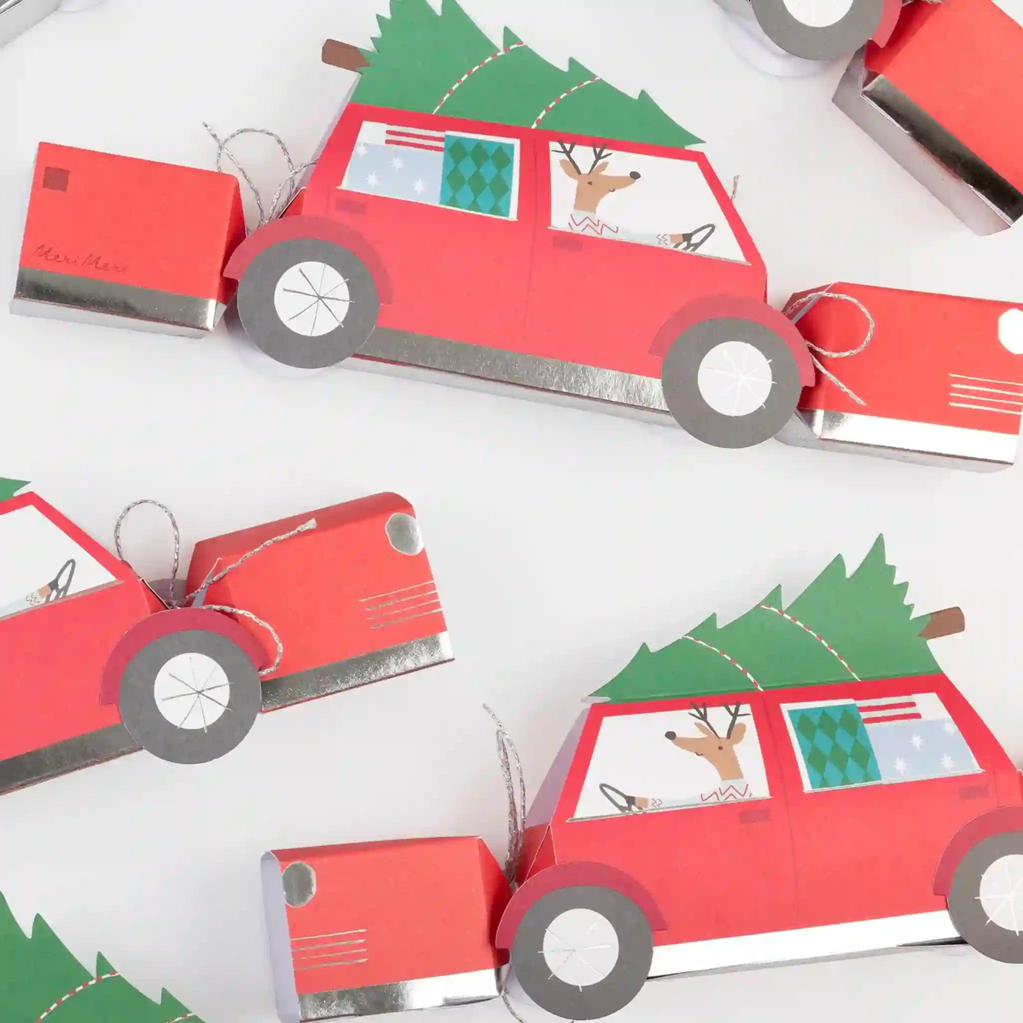 Red paper cars with Christmas trees and reindeer on a white background