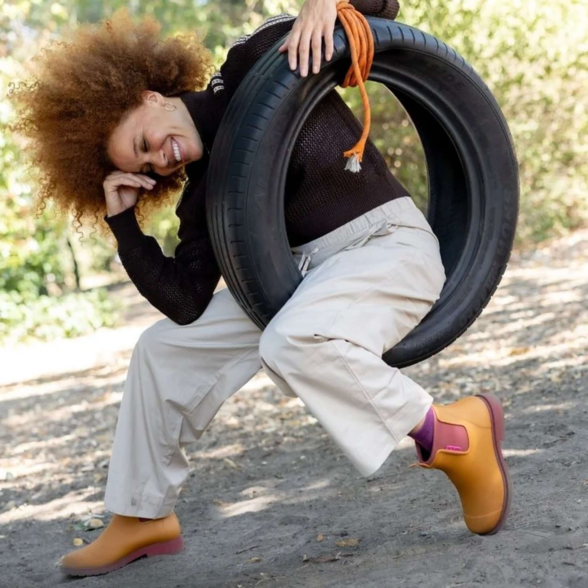 A woman enjoying the outdoors wearing Merry People Bobbi Ankle Boots - Ochre, playing with a tire swing.