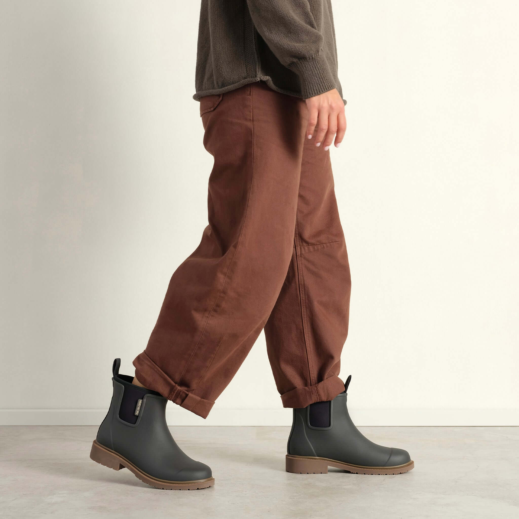 Person wearing Merry People Bobbi Ankle Boots - Charcoal with brown pants in a stylish pose.