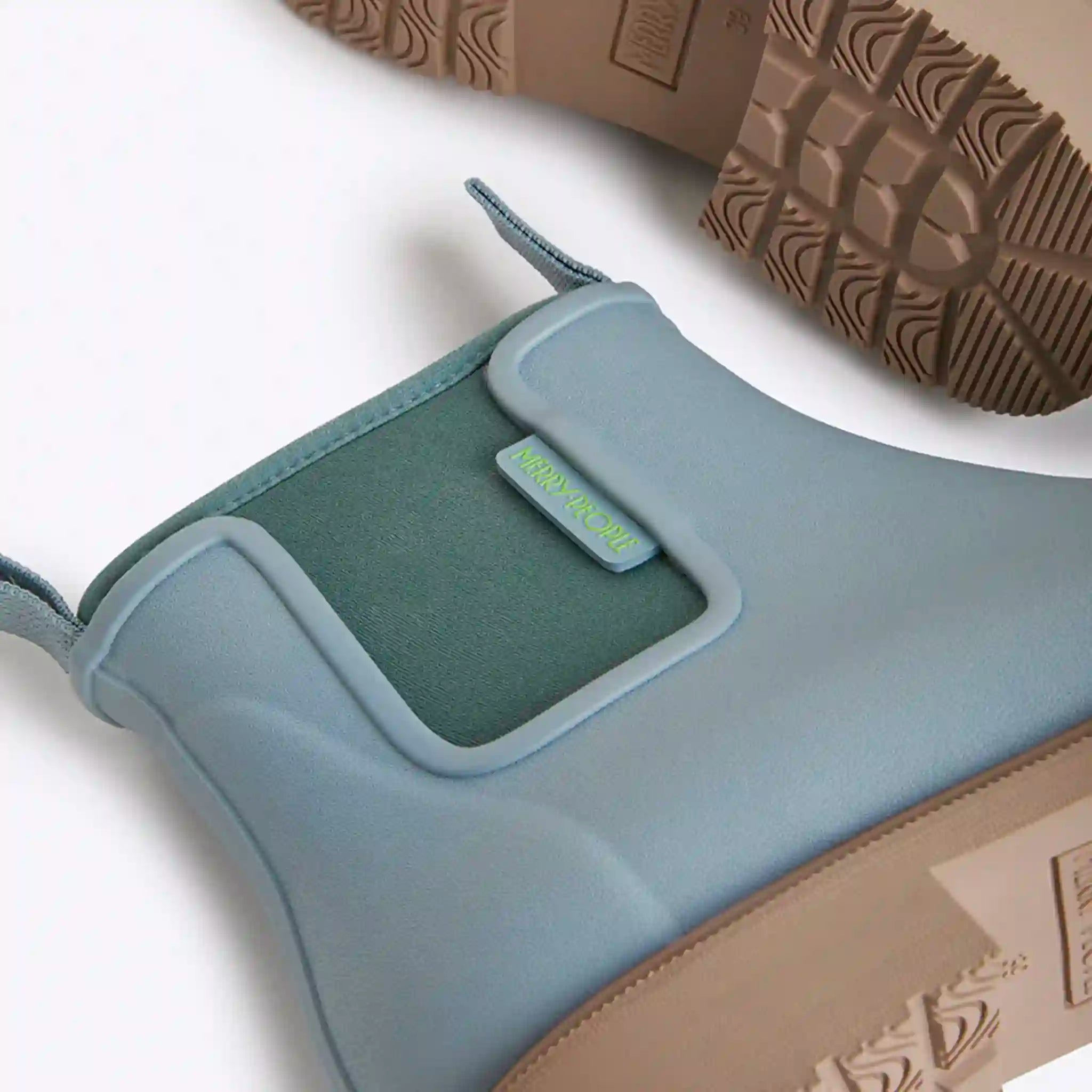 Close-up of a blue shoe with a green label on a white background