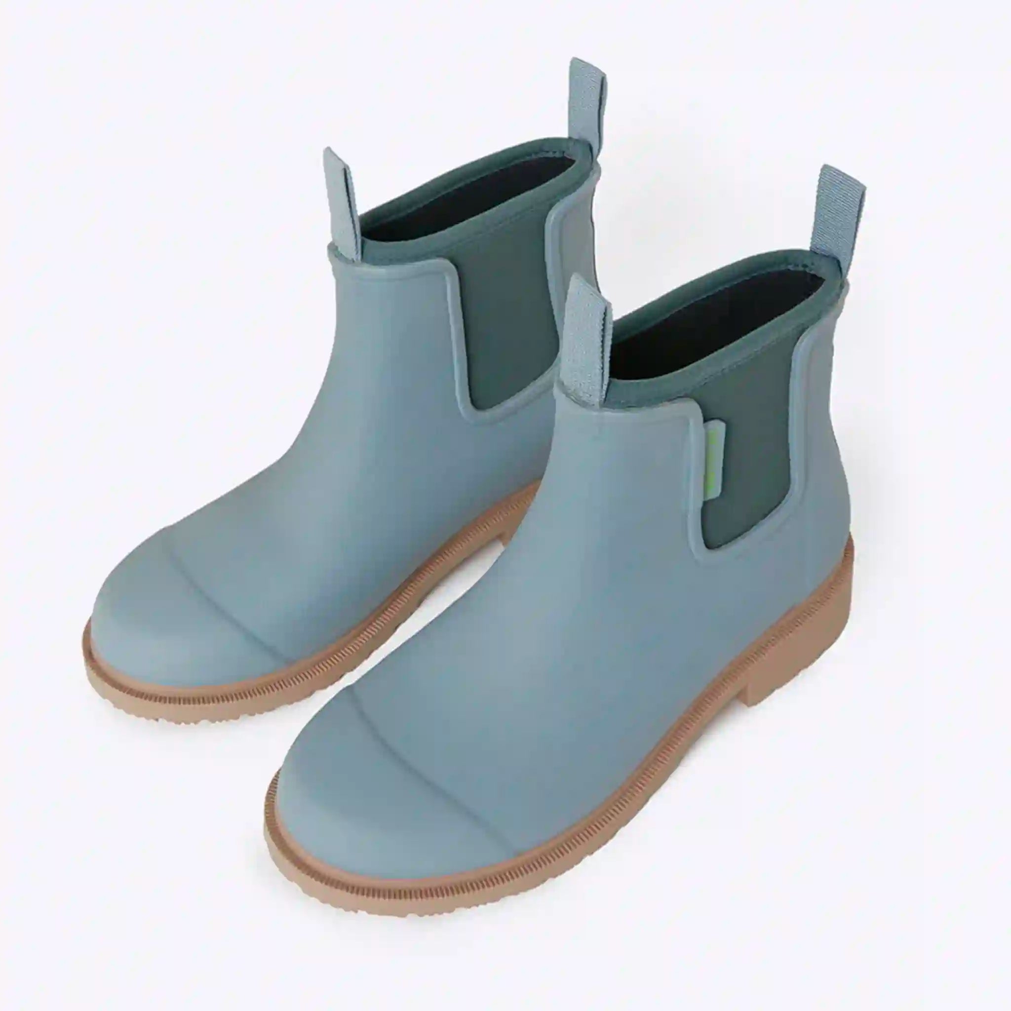 Pair of light blue rubber boots with brown soles on a white background