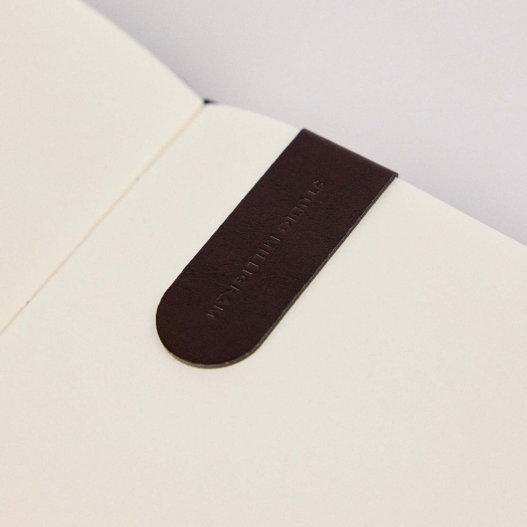 Milligram Recycled Leather Magnetic Page Markers - Burgundy marking a page in a notebook.