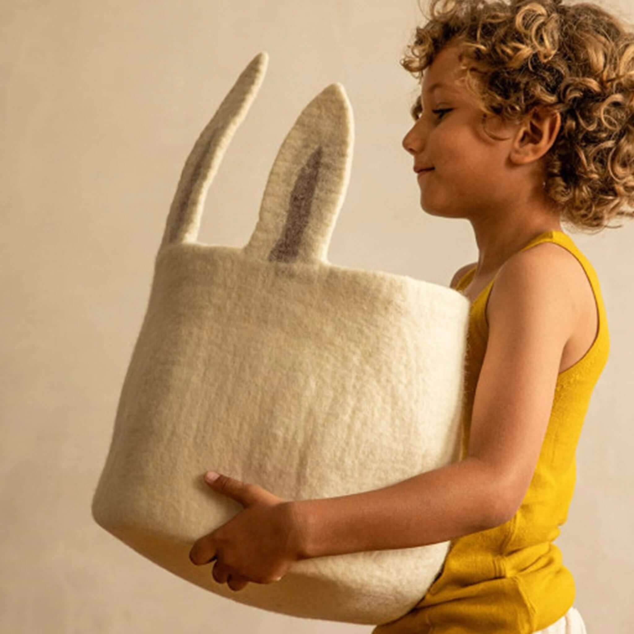 Muskhane Felt Basket - Pasu Bunny Natural held by a child, showcasing its playful design and practical use for storage.