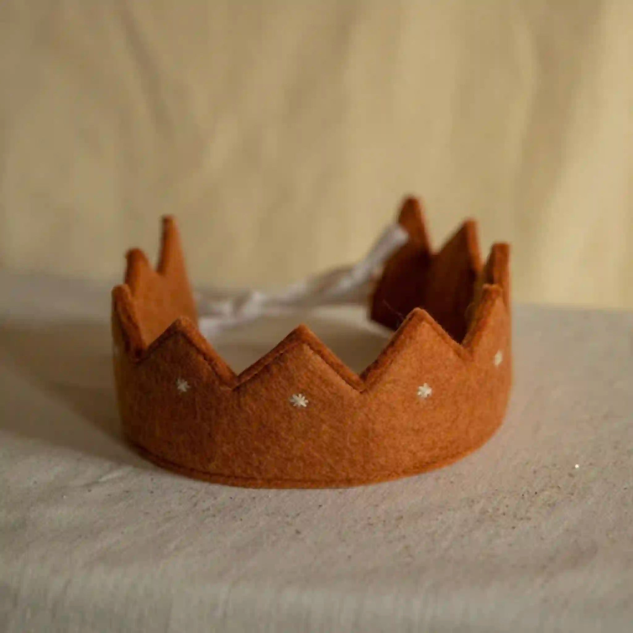 Brown felt crown with star decorations on a beige background