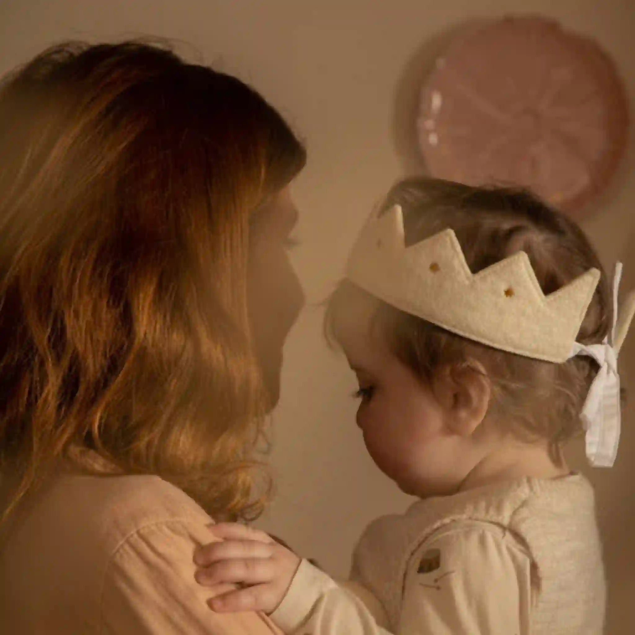 Woman and child wearing a crown in a warm-toned room