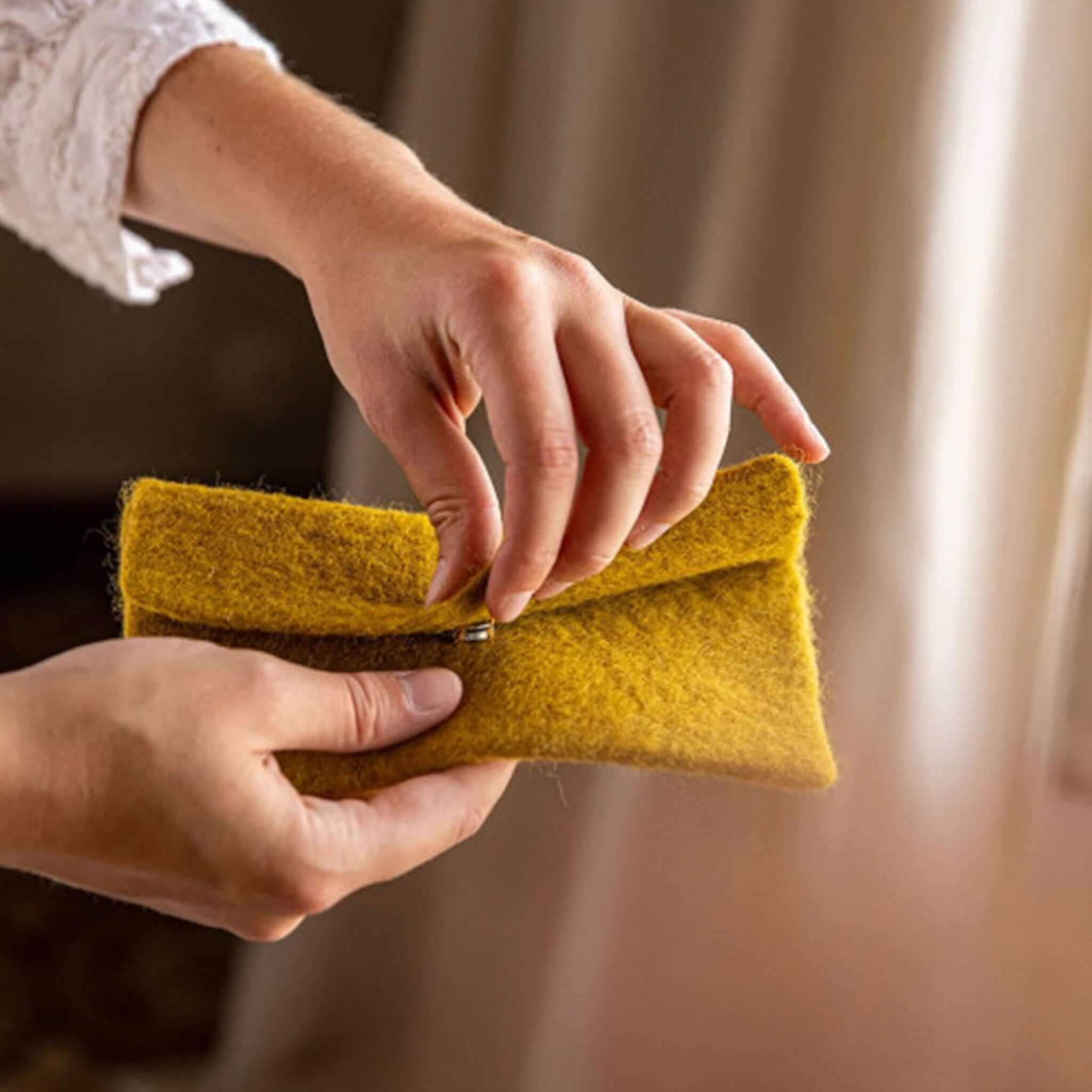 Person holding a handmade Muskhane Felt Glasses Case - Pistachio in soft wool felt.