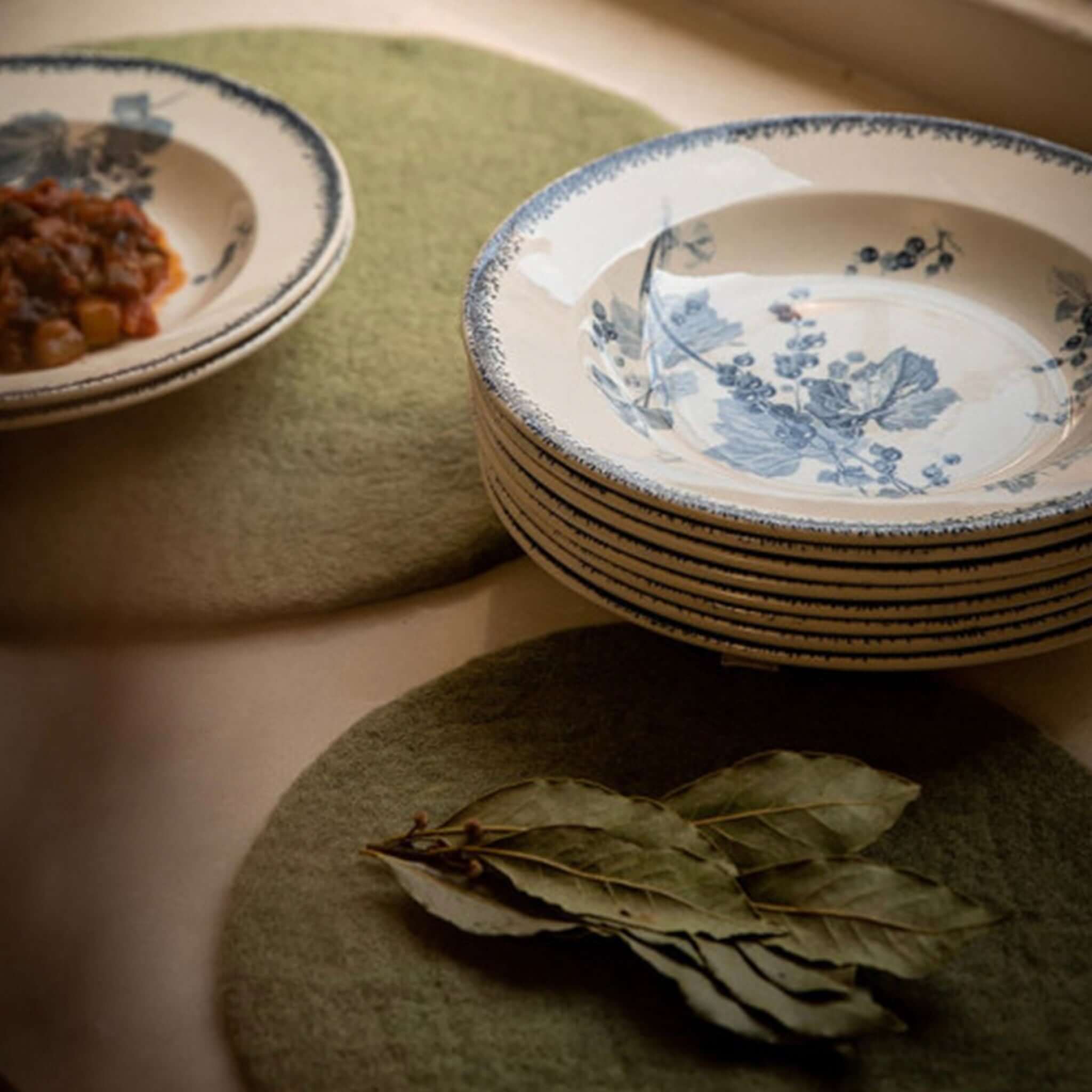 Muskhane Felt Plain Round Placemat - Sage Large under blue and white plates with bay leaves.