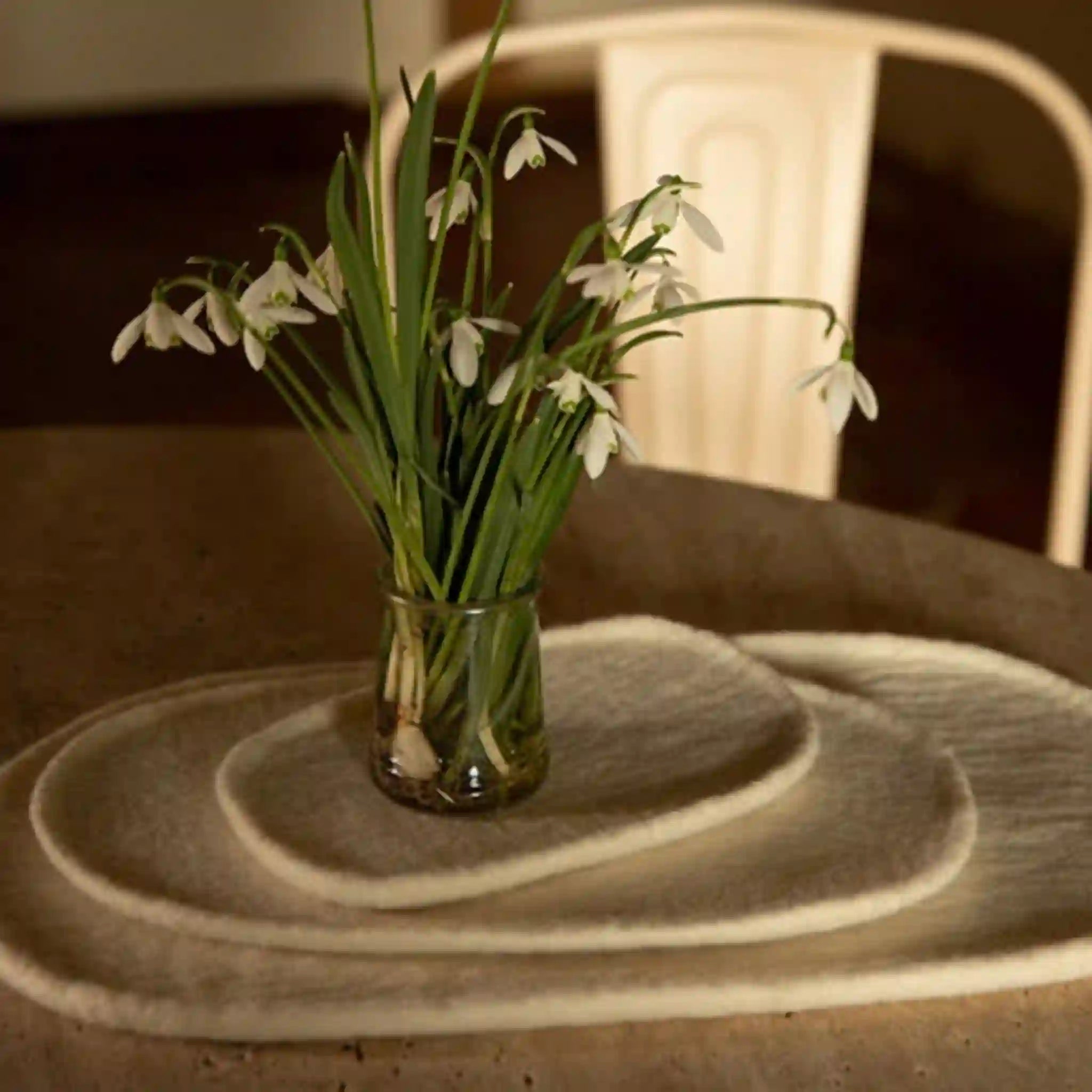 Clear glass vase with snowdrops on a textured surface