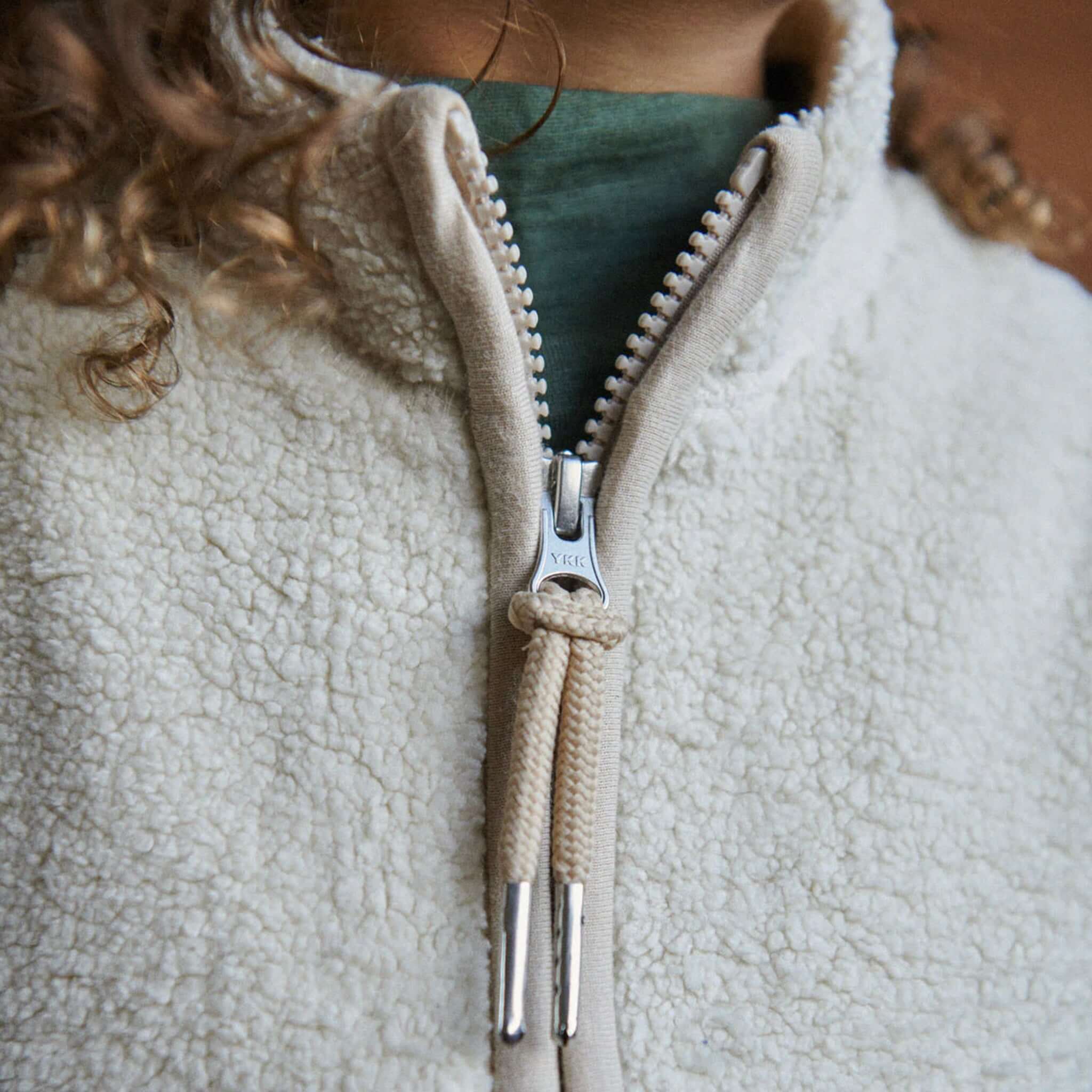 Alt Tag: Nature Baby Flint Vest - Oatmeal close-up of recycled polyester fleece with YKK zip front, high neckline and cosy cream texture