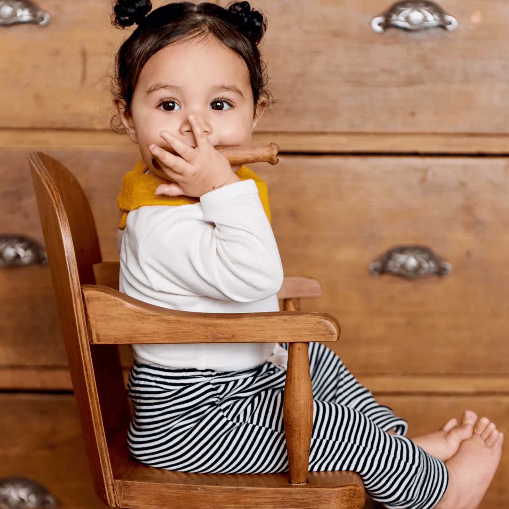 Child sitting on a wooden chair with a wooden background
