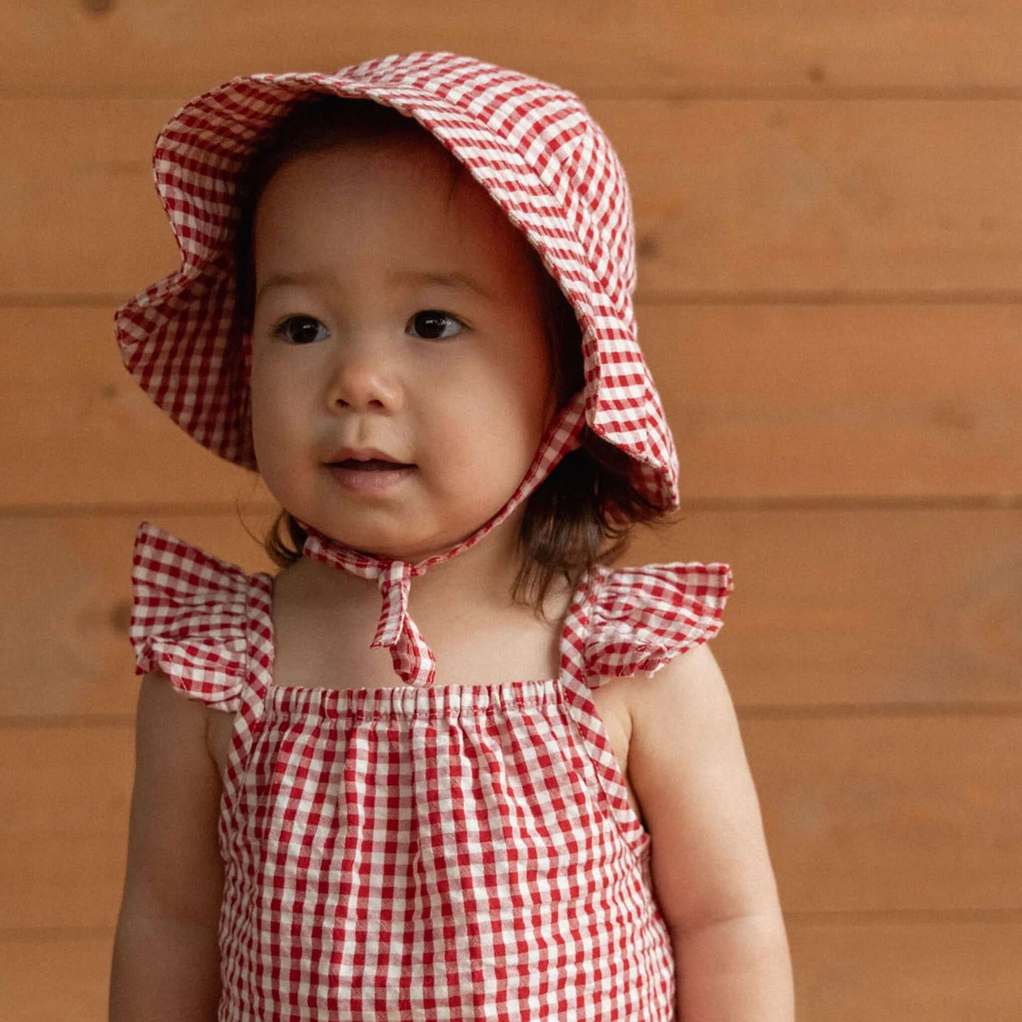 Nature Baby Organic Cotton Gingham Sunhat - Red Check on a toddler, featuring a woven design and large brim for sun protection.