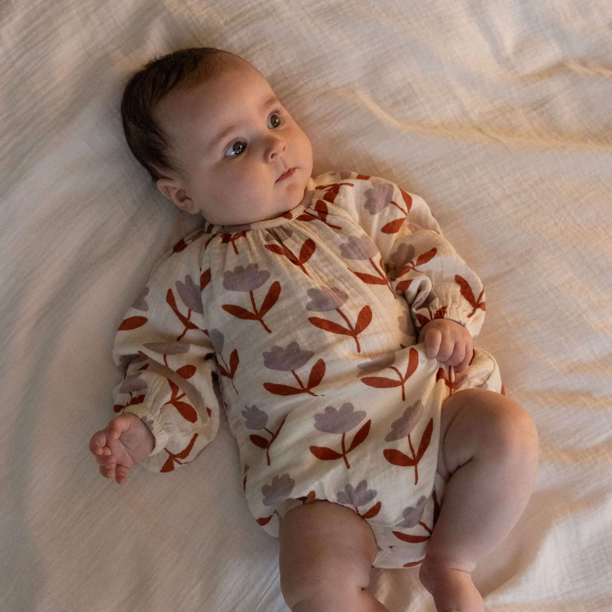 Nature Baby Organic Cotton Meadow Long Sleeve Muslin Bodysuit - Fleurette on a baby, featuring a floral print.