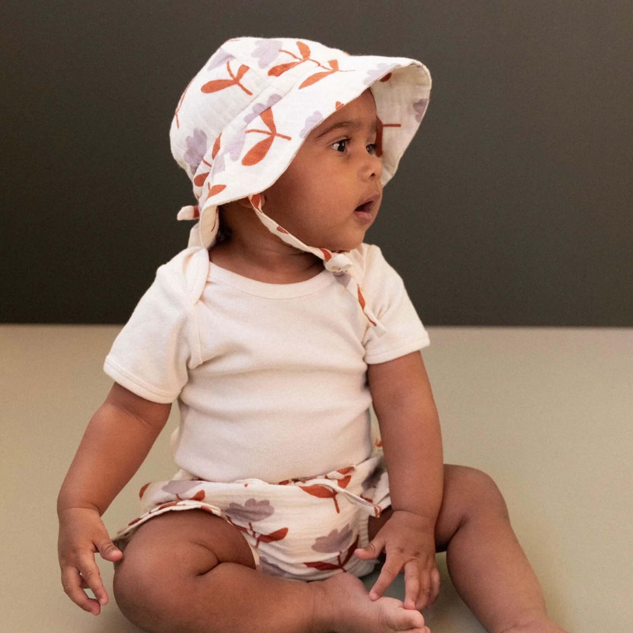 Nature Baby Organic Cotton Muslin Petal Bloomers - Fleurette worn by a baby, paired with a matching hat.
