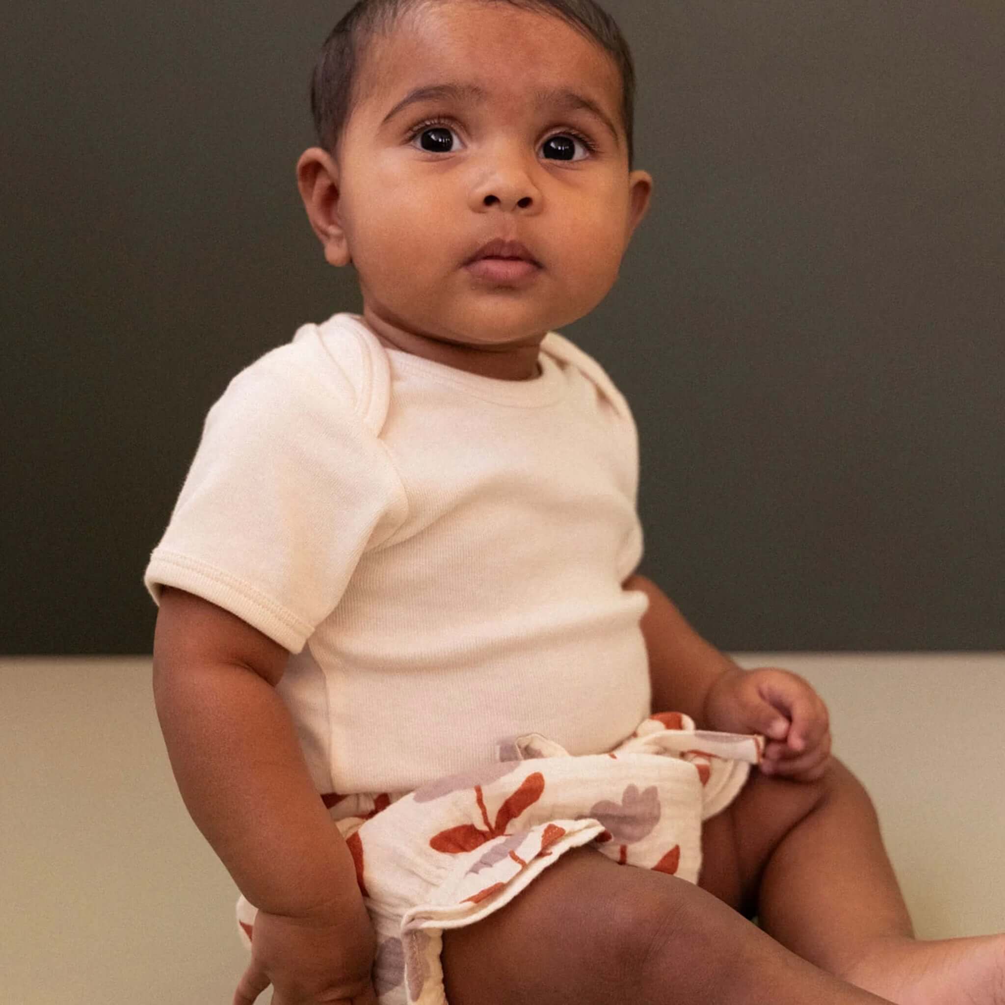 Nature Baby Organic Cotton Muslin Petal Bloomers - Fleurette worn by a baby sitting down, showcasing the floral print.
