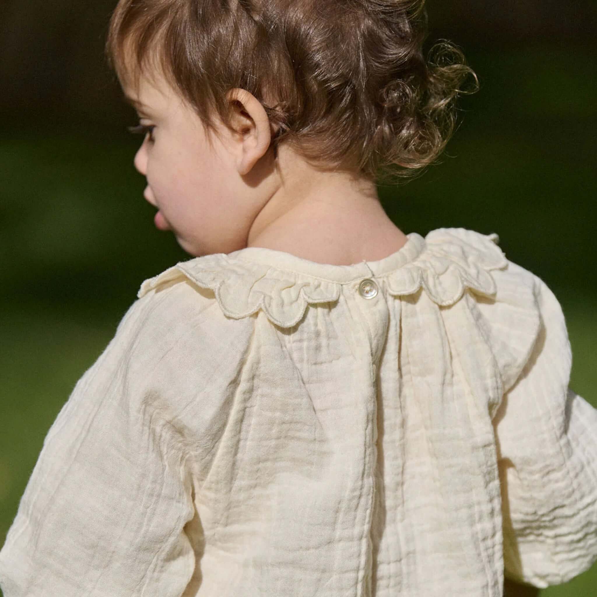 Nature Baby Organic Cotton Ruffle Cameron Blouse - Natural on a child, featuring a scalloped ruffle collar and button detail.