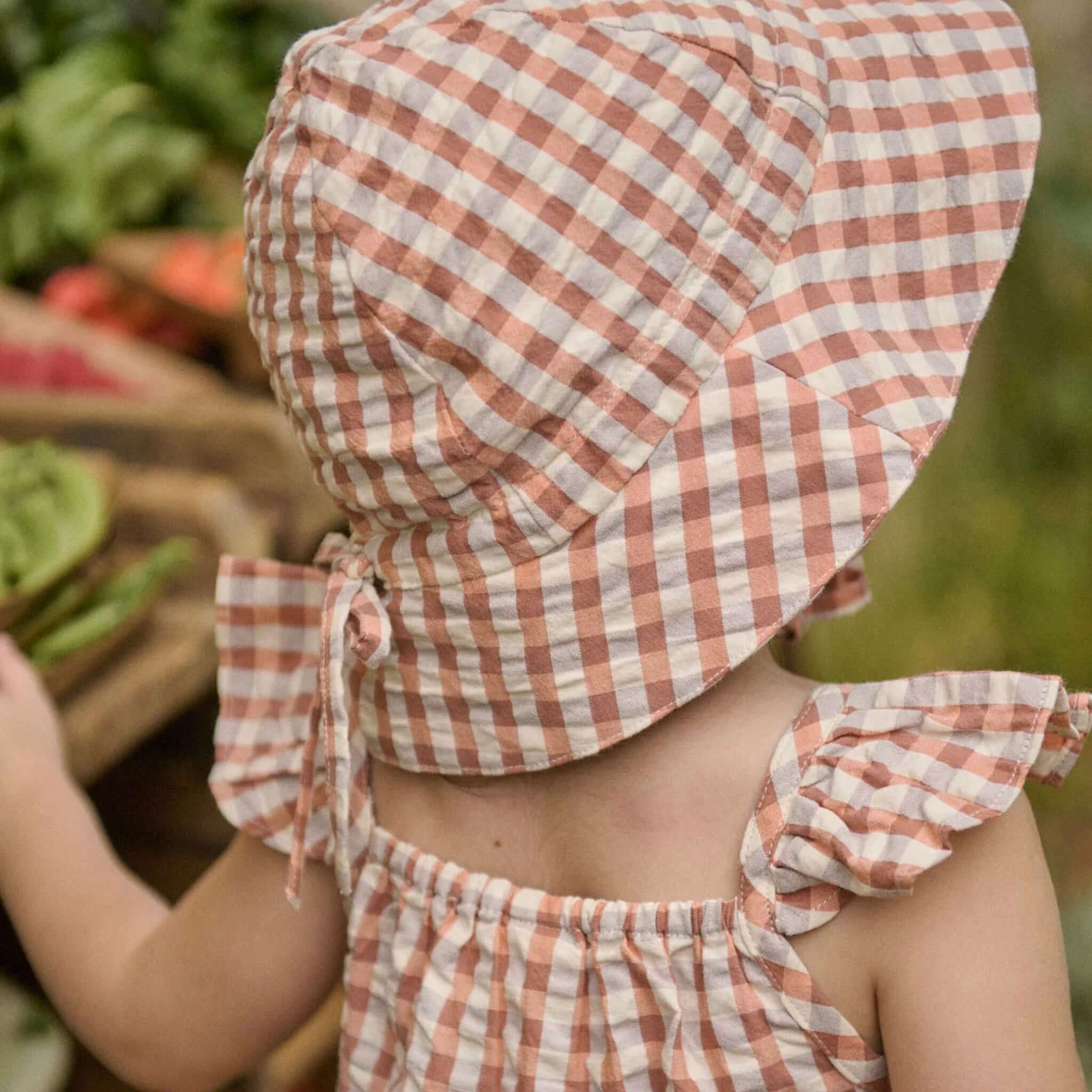 Nature Baby Organic Cotton Sunhat - Dandelion Gingham on a baby, featuring a large brim and gingham check pattern.