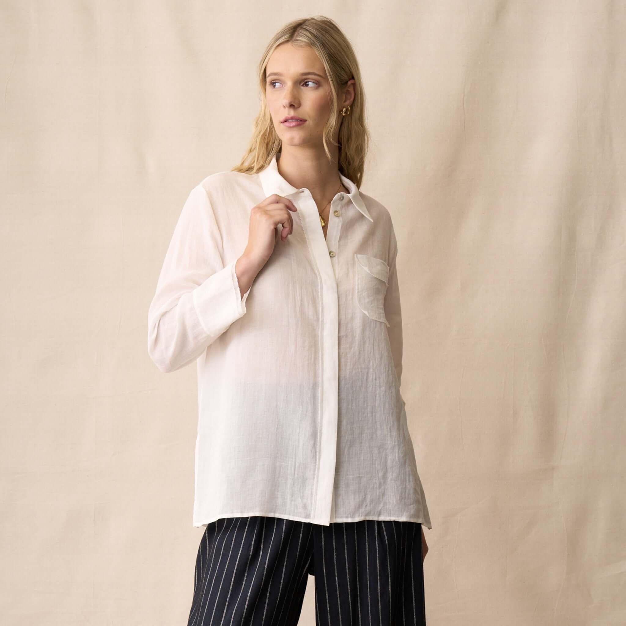 Model wearing the Neris Phoebe Top - White, a sheer button-front shirt with picot trim.