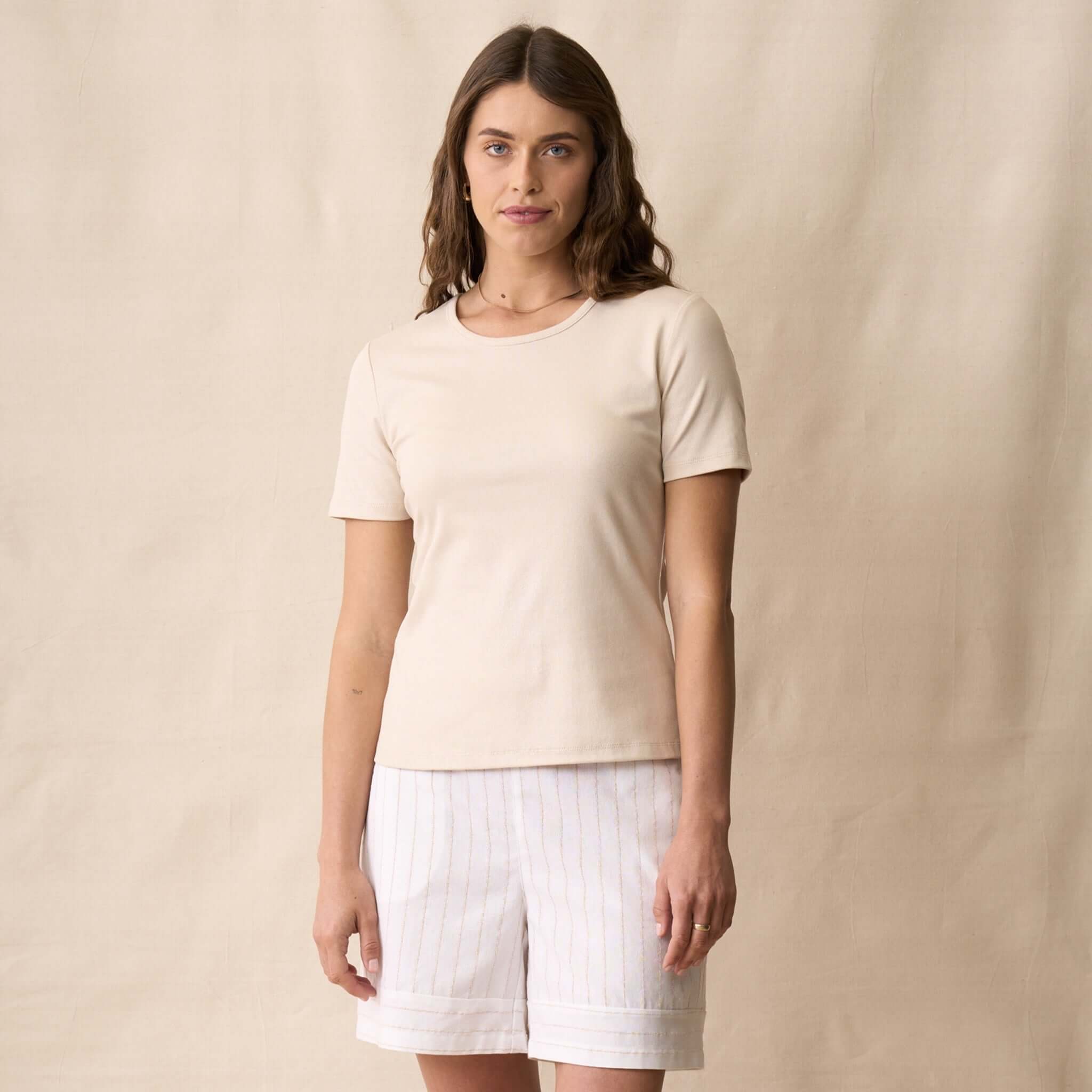 Neris Ziggy Tee - Sand worn with white striped shorts, showcasing its classic crew neckline and soft cotton fabric.