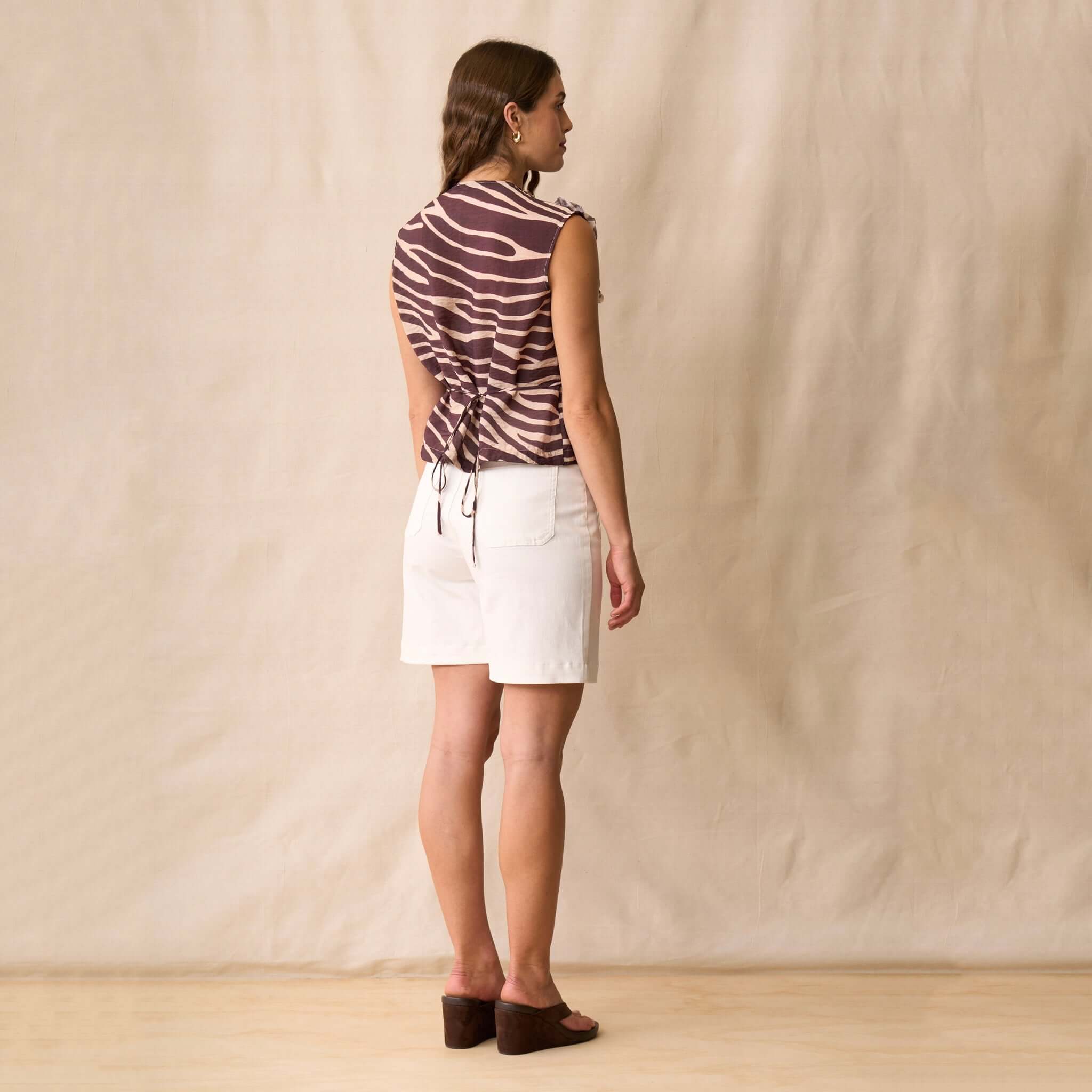Neris Dazzle Shirt - Mahogany worn with white shorts, showcasing back details and elegant tie accents.