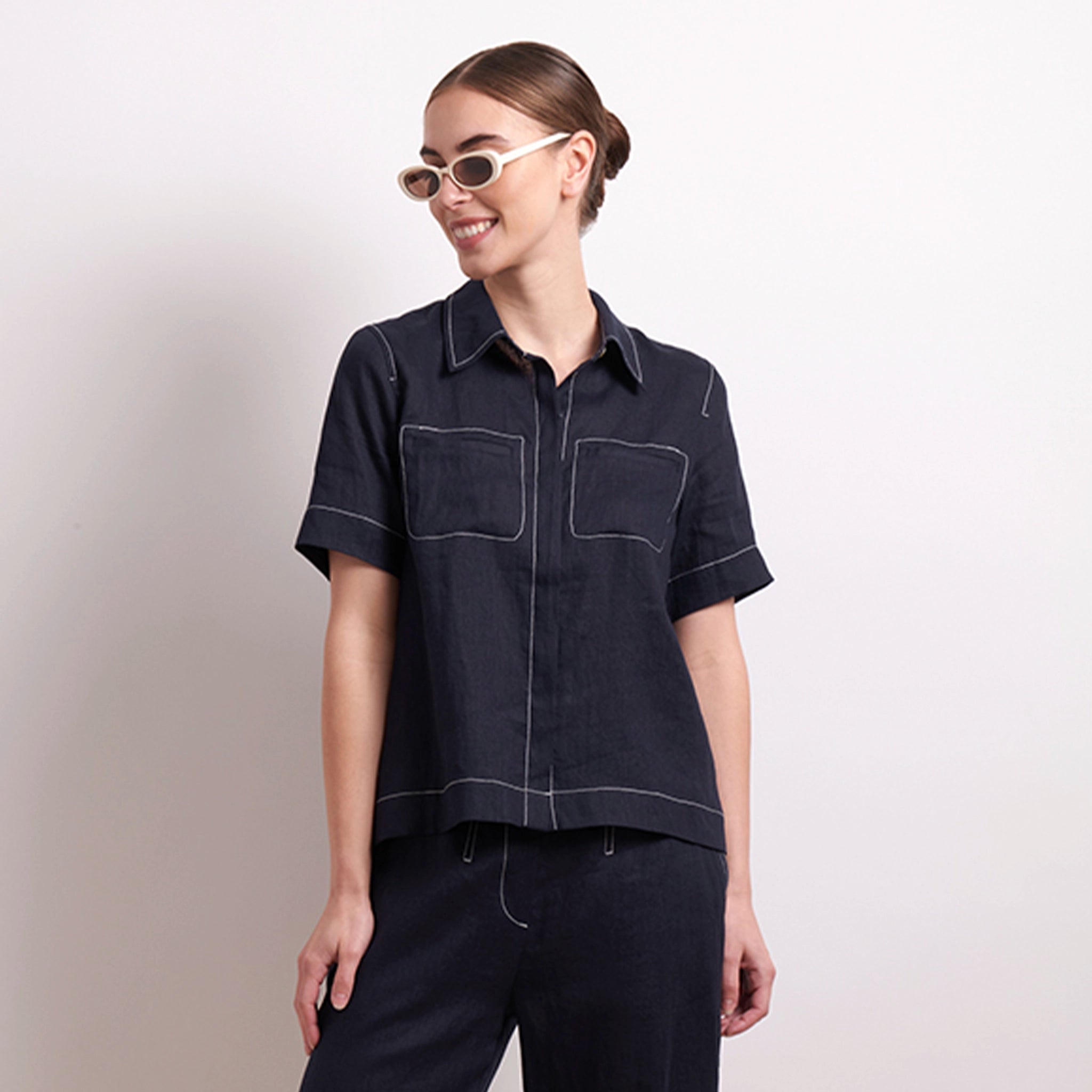 Woman wearing a dark denim shirt and pants on a plain background