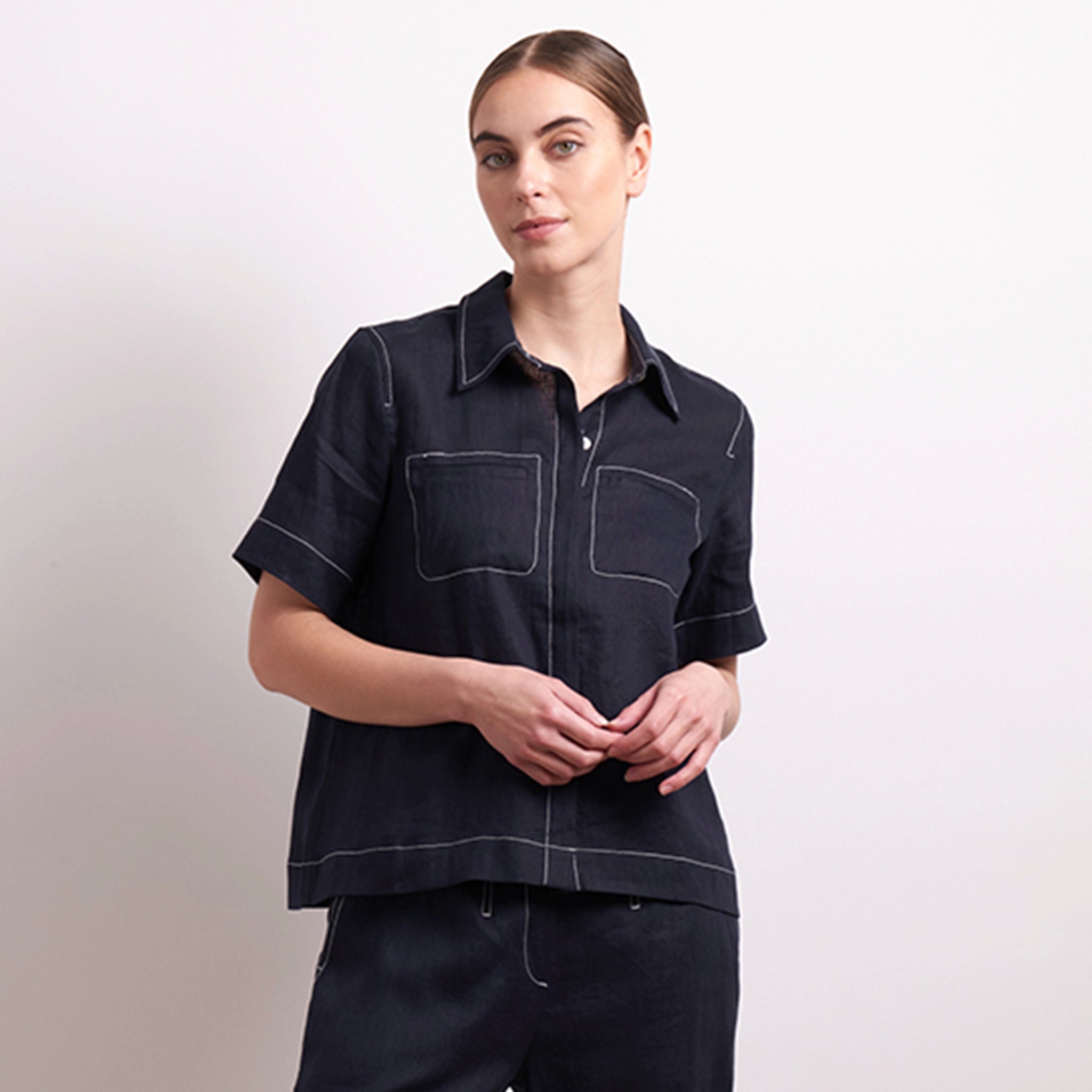 Person wearing a dark denim shirt and pants on a light background