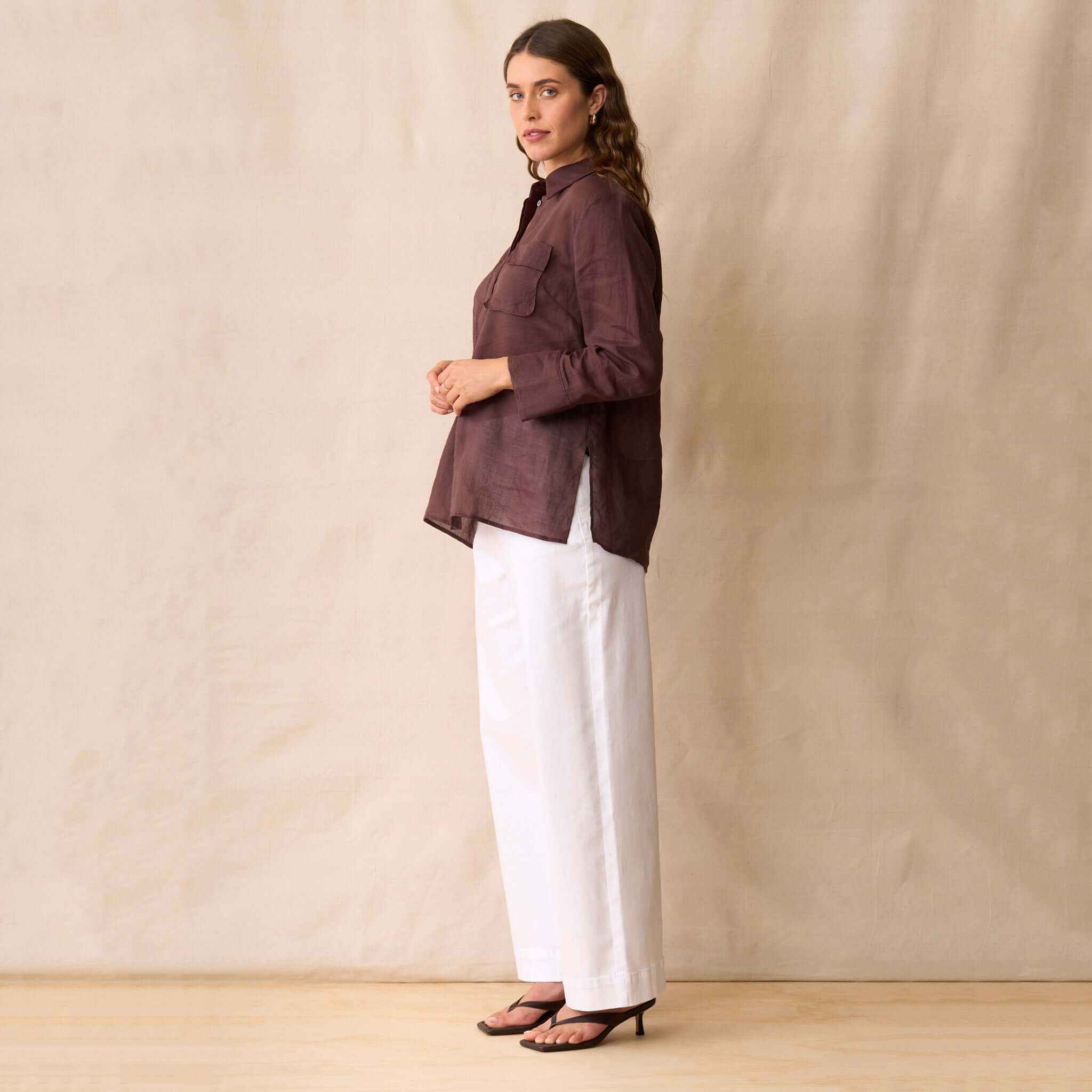 Neris Phoebe Top - Mahogany worn with white trousers, showcasing the sheer, structured design and classic collar.